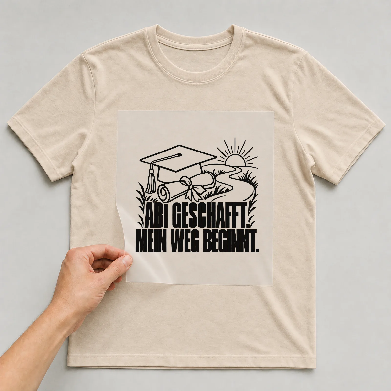 Bügelbild „Abi geschafft. Mein weg beginnt.“ auf beigem T-Shirt, Folie wird aufgelegt
