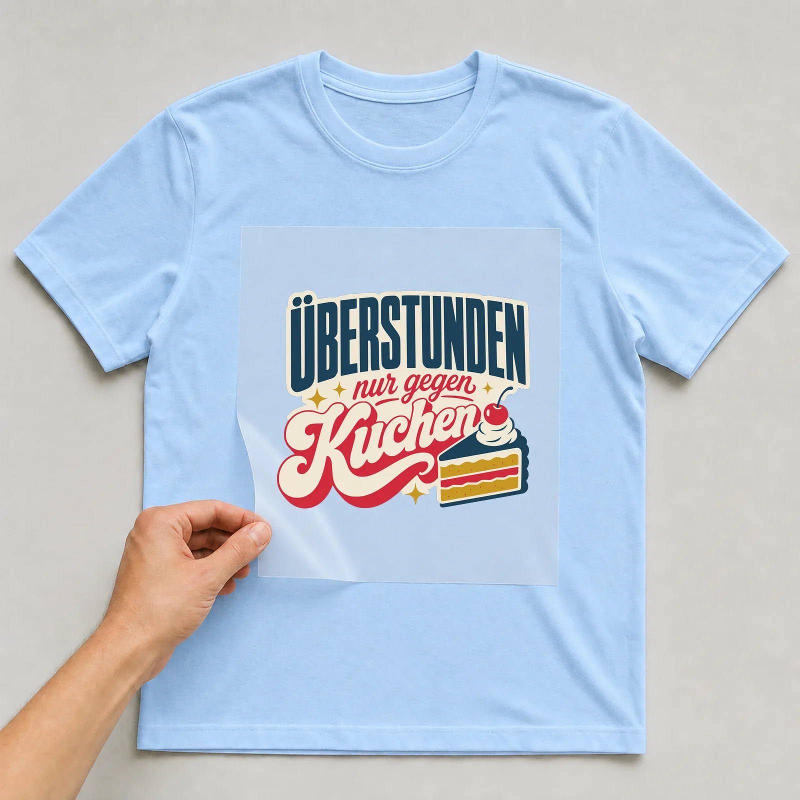 Bügelbild Überstunden nur gegen Kuchen auf hellblauem T-Shirt, Folie wird aufgelegt