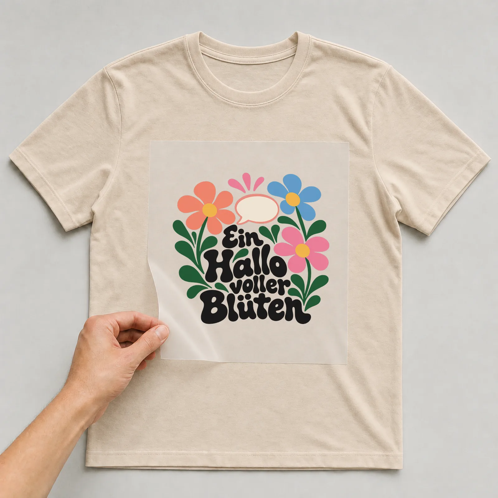 Bügelbild „Ein Hallo voller Blüten“ auf beigem T-Shirt, Folie wird aufgelegt