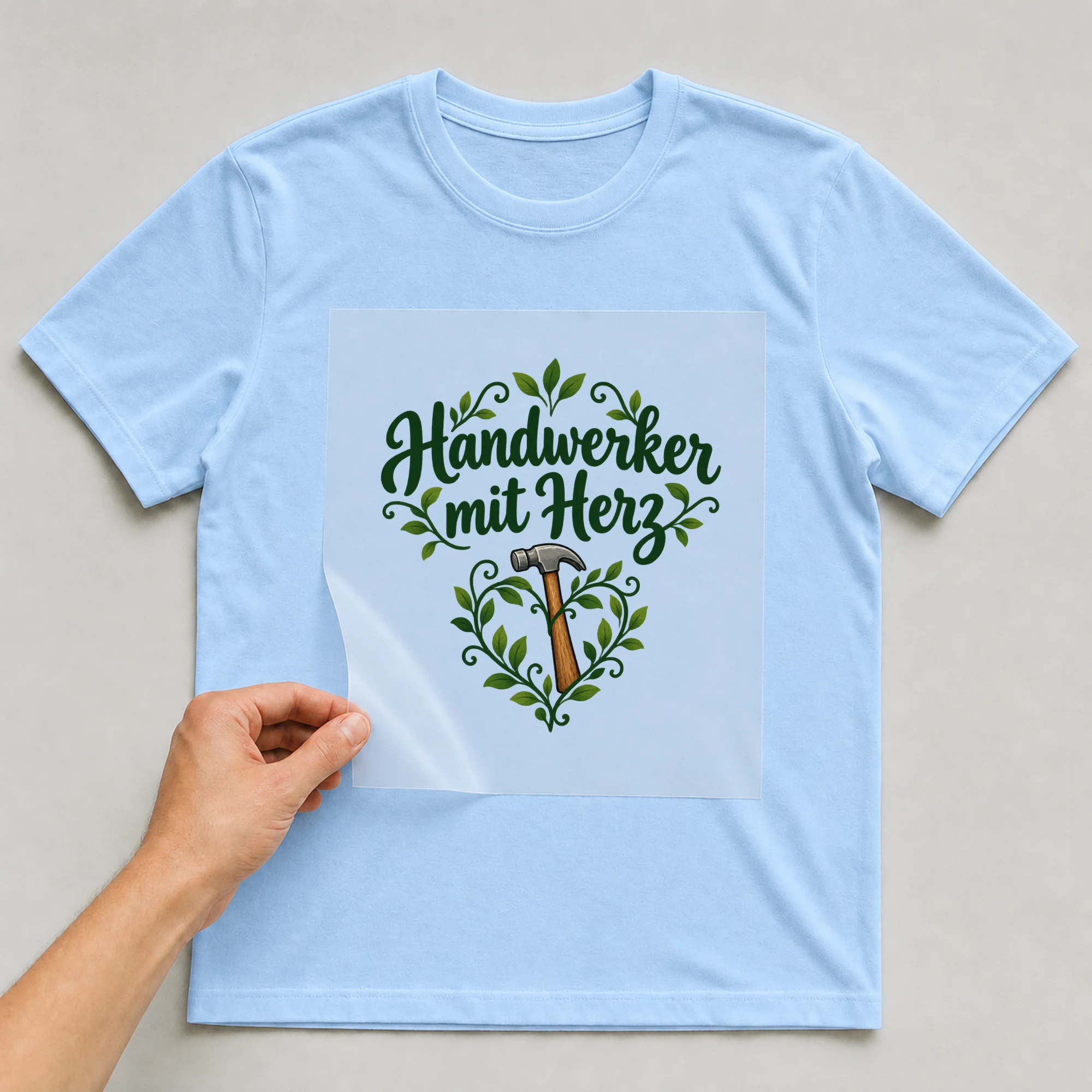 Bügelbild „Handwerker mit Herz“ auf babyblauem T-Shirt, Folie wird aufgelegt