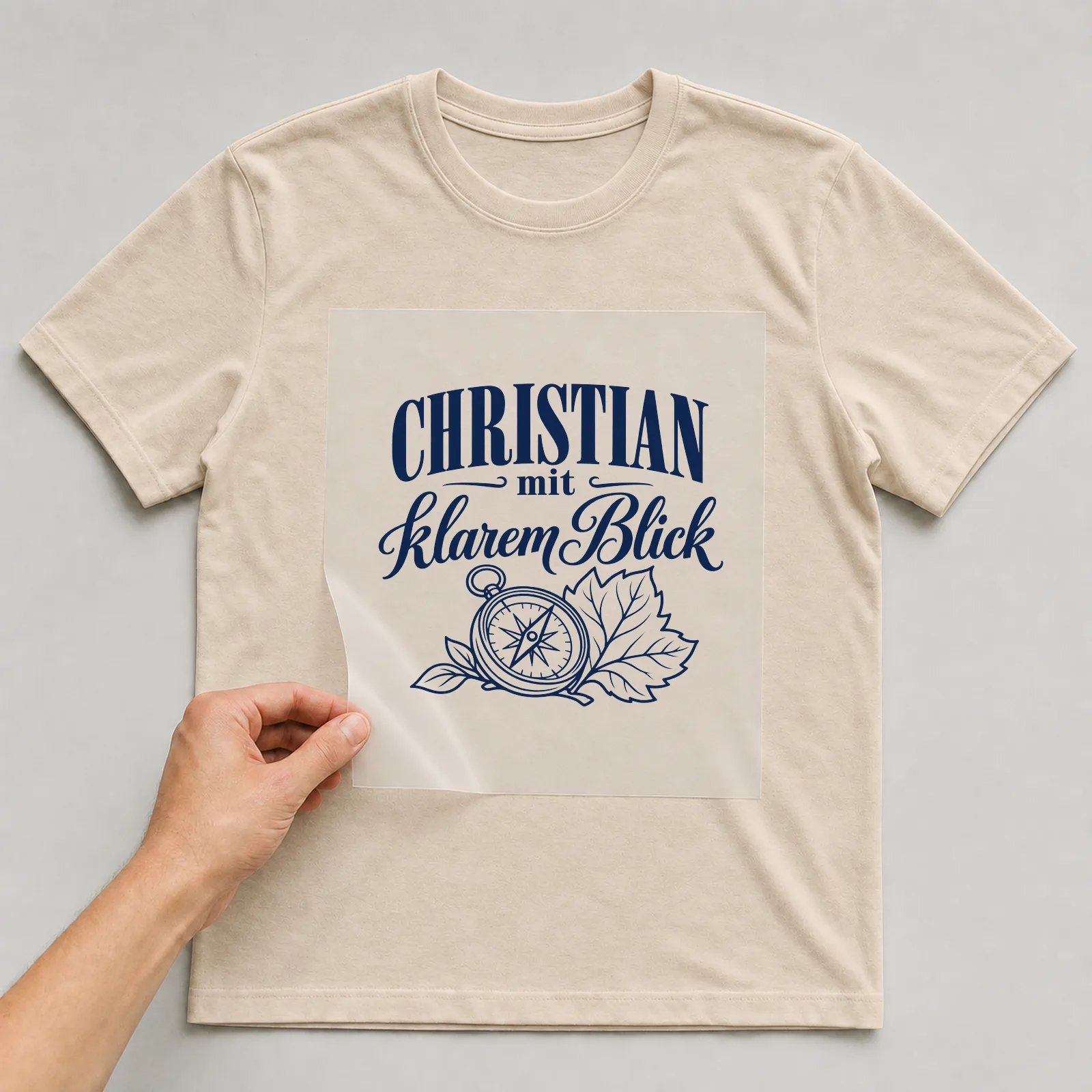 Bügelbild „Christian mit klarem Blick“ auf beigem T-Shirt, Folie wird aufgelegt
