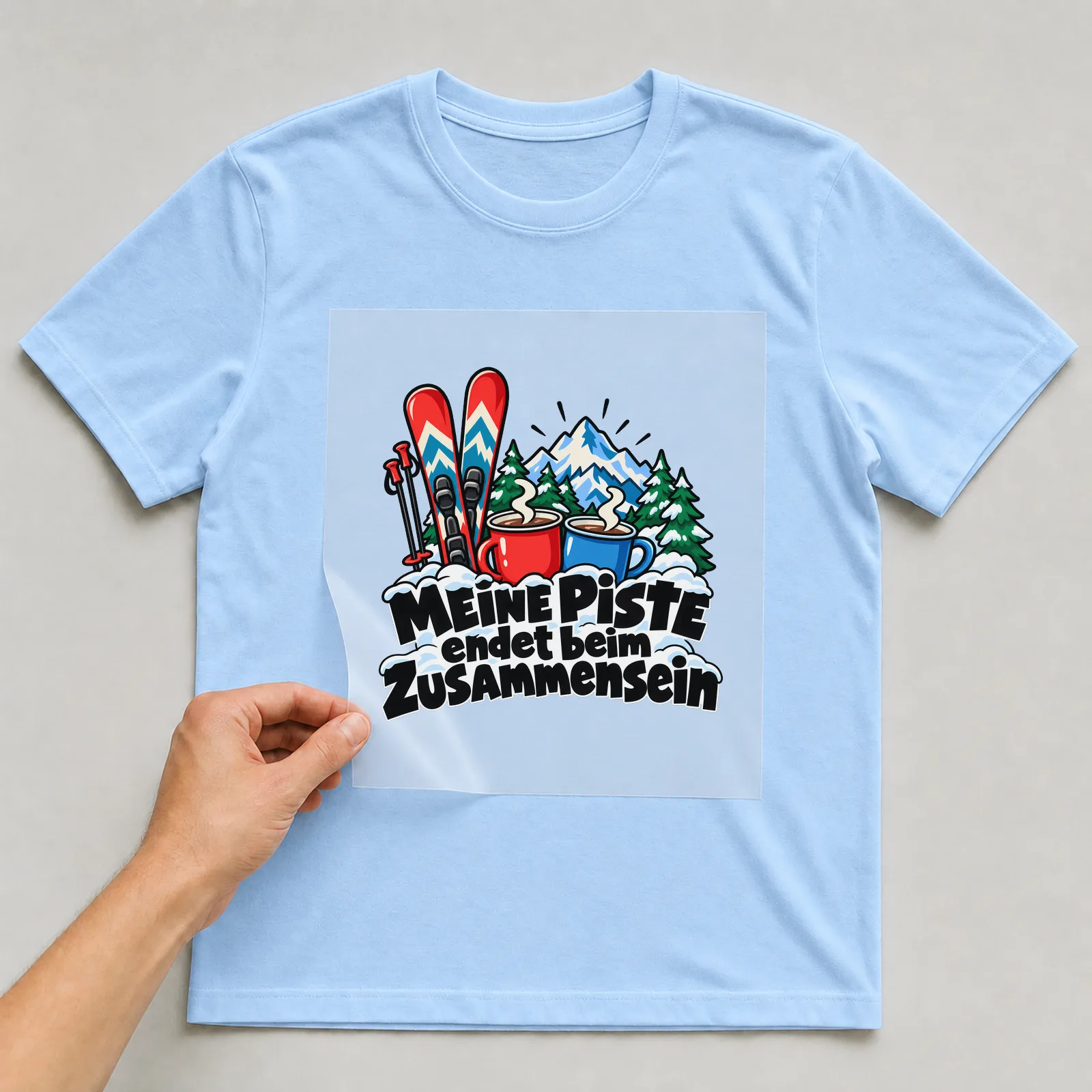 Bügelbild „MEINE PISTE endet beim ZUSAMMENSEIN“ auf hellblauem T-Shirt, Folie wird aufgelegt
