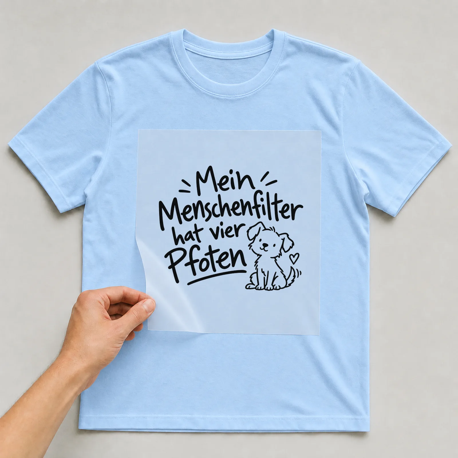 Bügelbild „Mein Menschenfilter hat vier Pfoten“ auf hellblauem T-Shirt, Folie wird aufgelegt