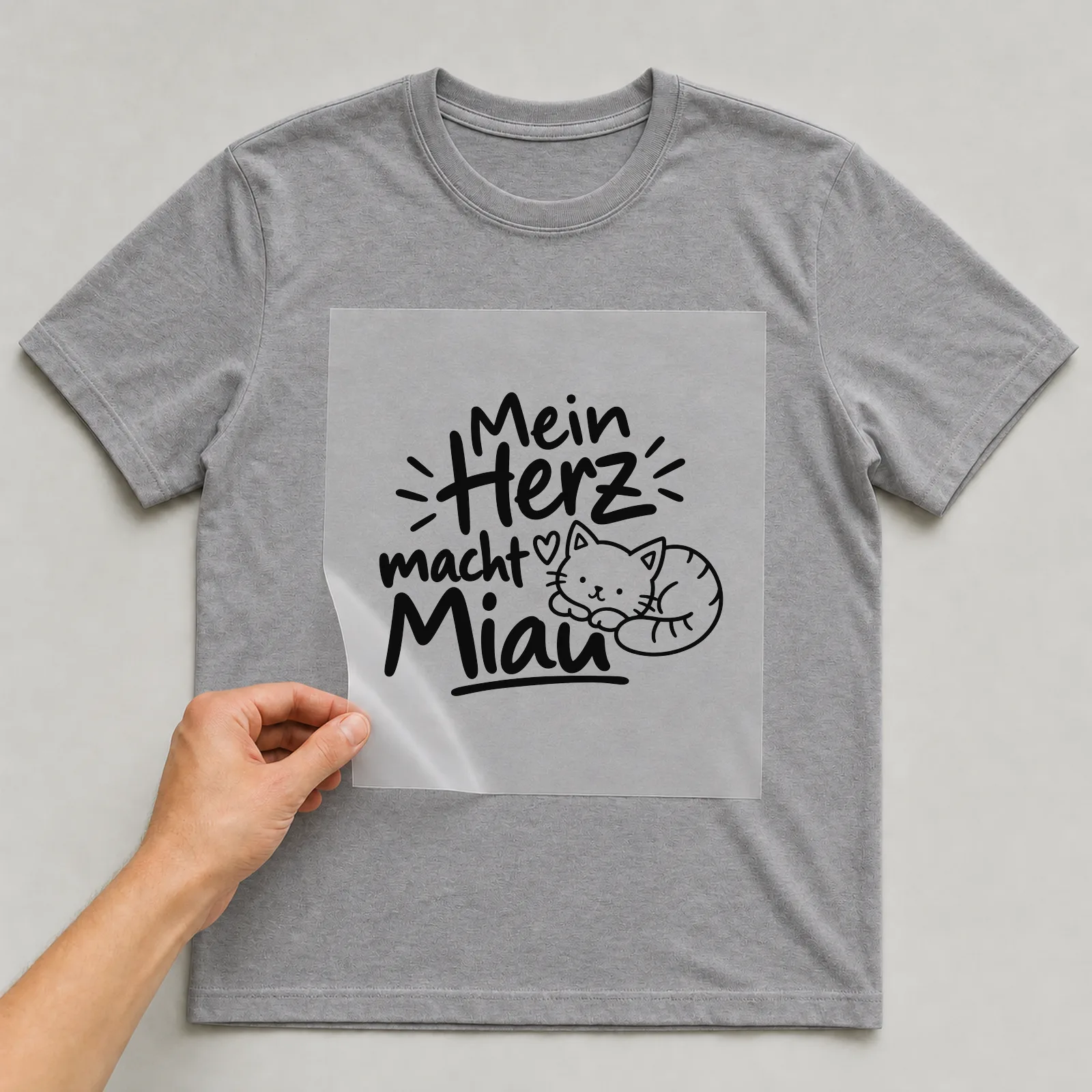 Bügelbild „Mein Herz macht Miau“ auf grauem T-Shirt, Folie wird aufgelegt