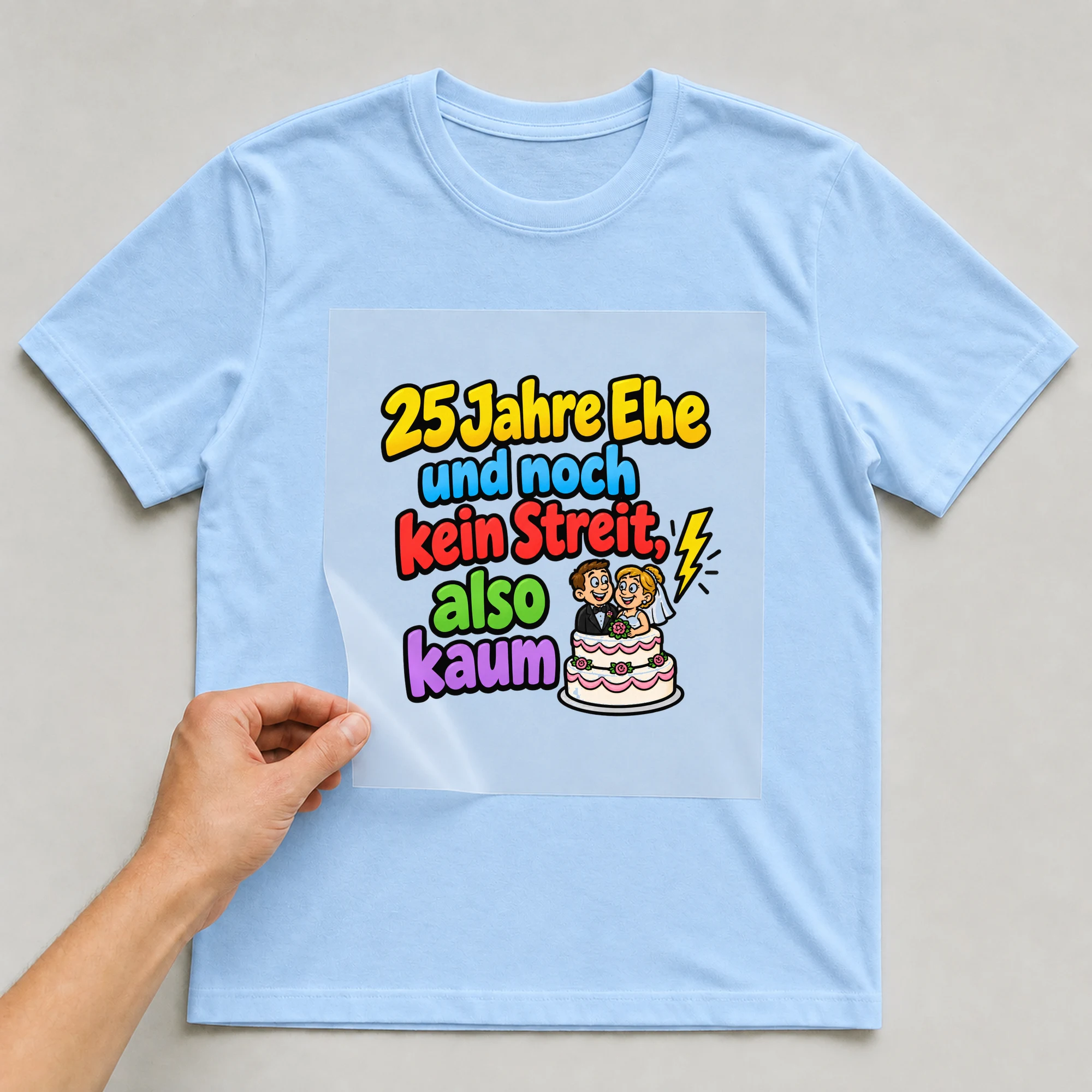 Bügelbild „25 Jahre Ehe und noch kein Streit, also kaum“ auf babyblauem T-Shirt, Folie wird aufgelegt