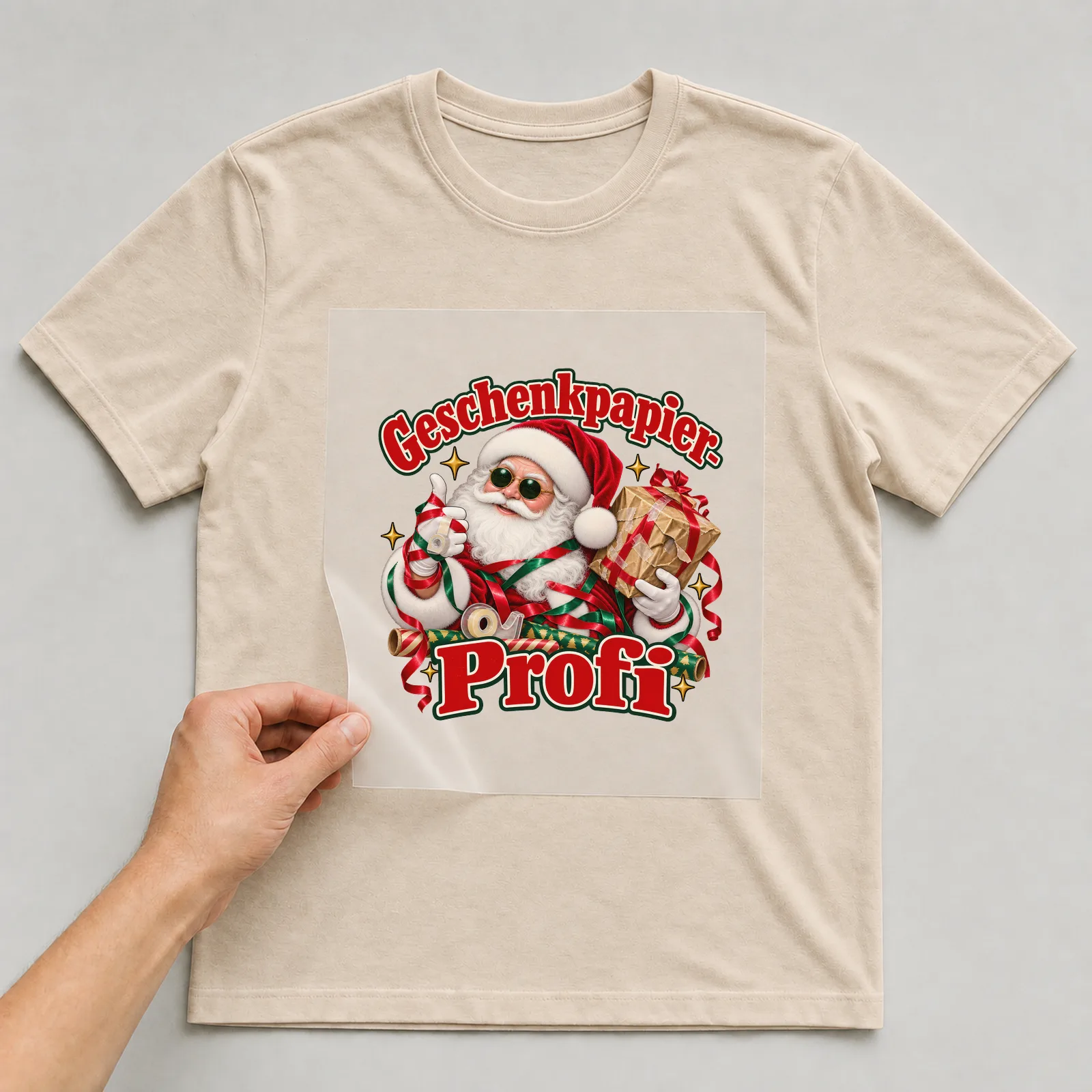 Bügelbild Geschenkpapier-Profi (Freche Weihnachtsklassiker) auf beigem T-Shirt, Folie wird aufgelegt