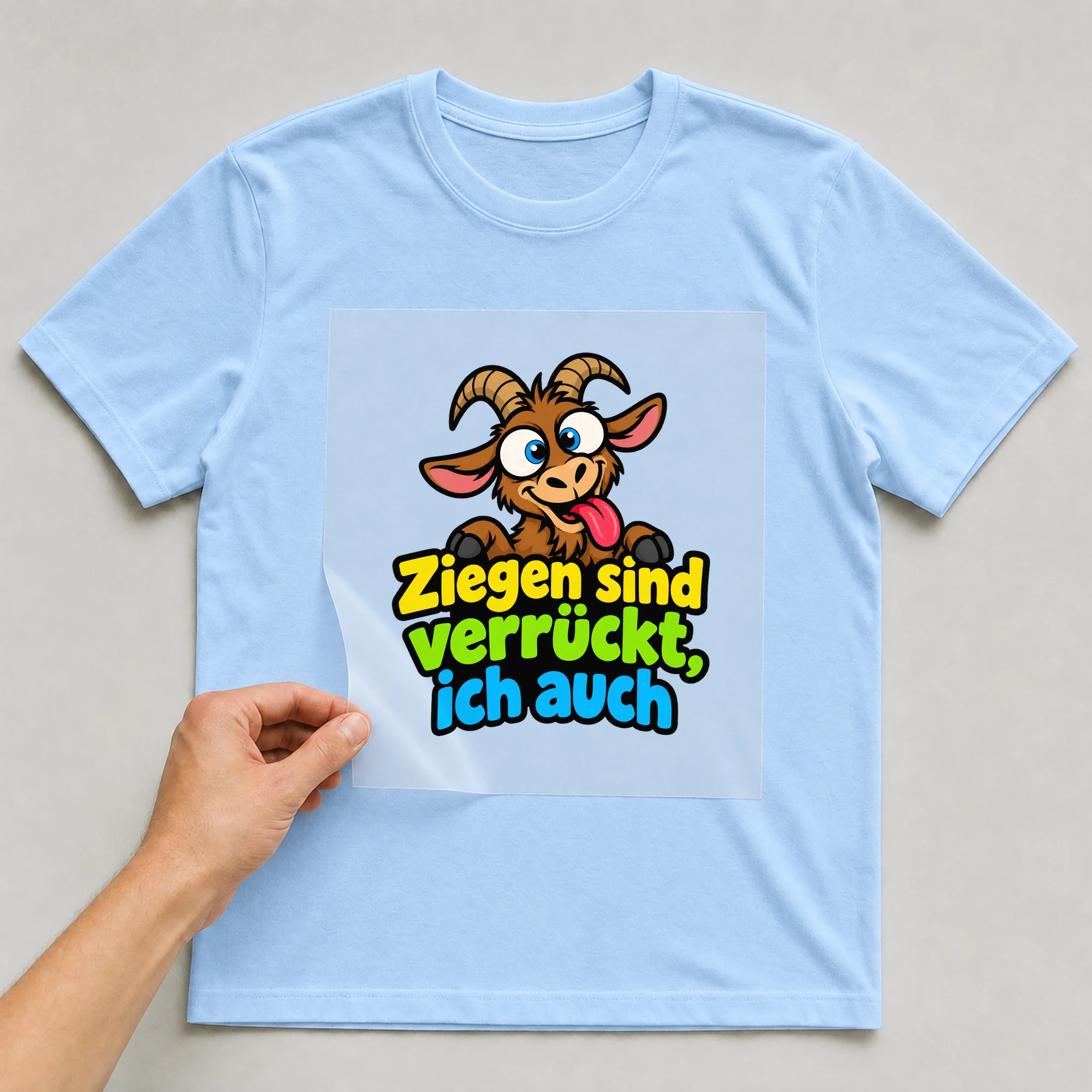 Bügelbild „Ziegen sind verrückt, ich auch“ auf babyblauem T-Shirt, Folie wird aufgelegt