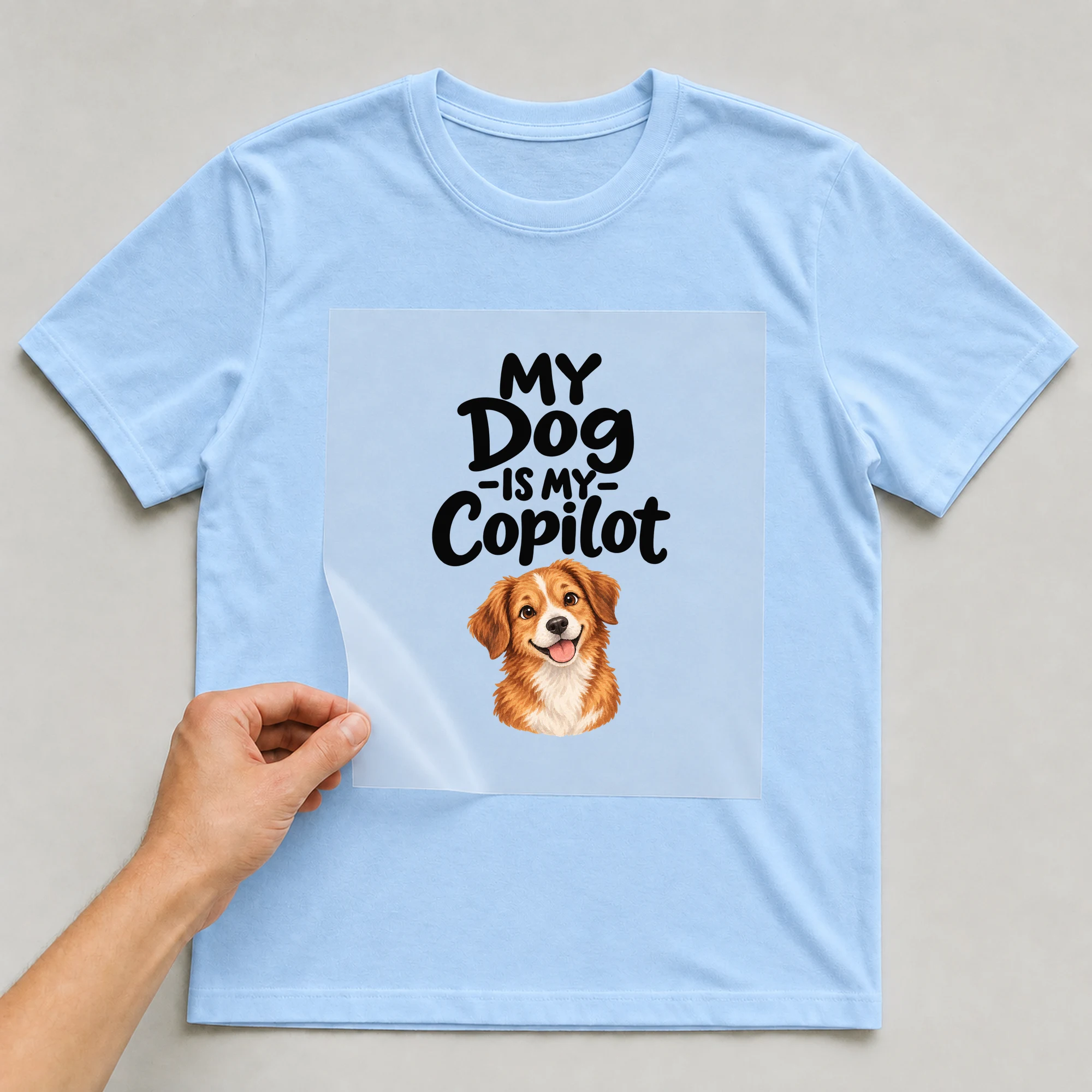 Bügelbild „My Dog -is My- Copilot“ auf babyblauem T-Shirt, Folie wird aufgelegt