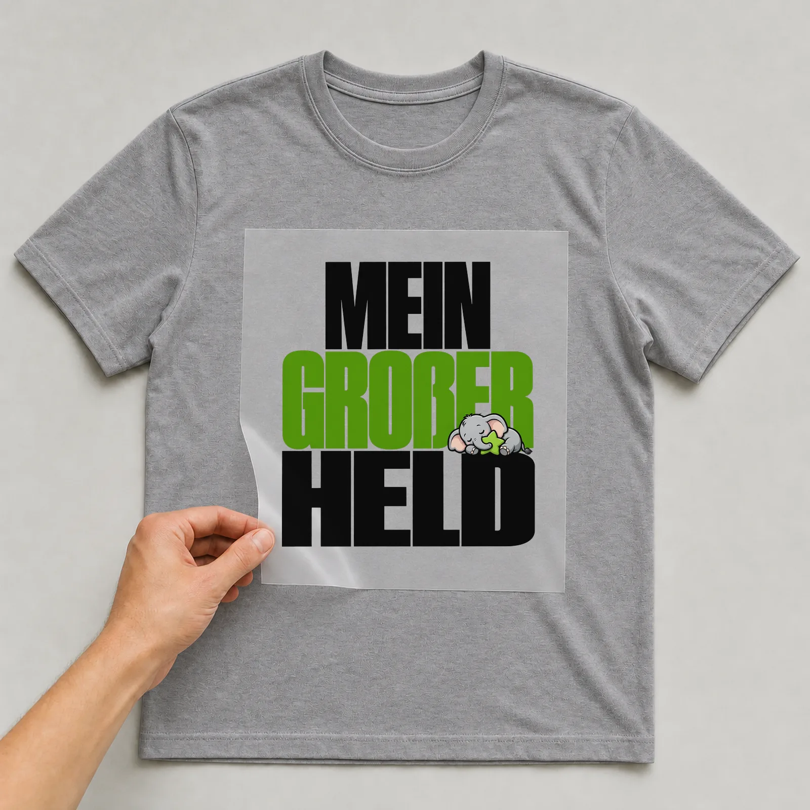 Bügelbild „Mein großer Held“ auf grauem T-Shirt, Folie wird aufgelegt