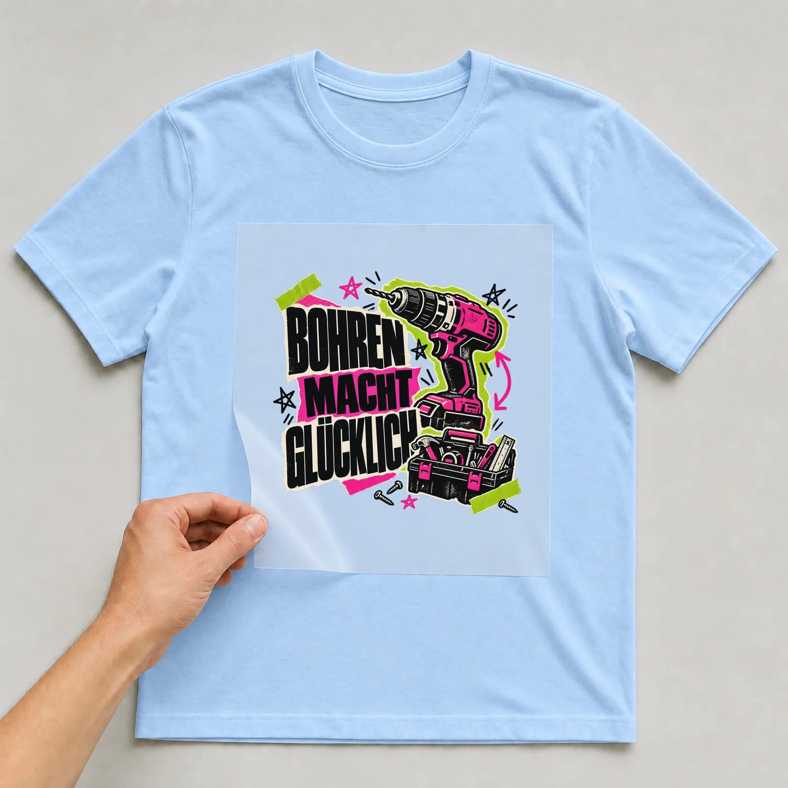 Bügelbild „Bohren macht glücklich“ auf hellblauem T-Shirt, Folie wird aufgelegt
