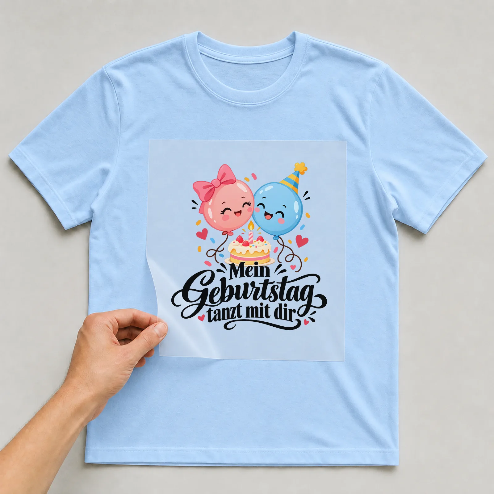Bügelbild „Mein Geburtstag tanzt mit dir“ auf hellblauem T-Shirt, Folie wird aufgelegt