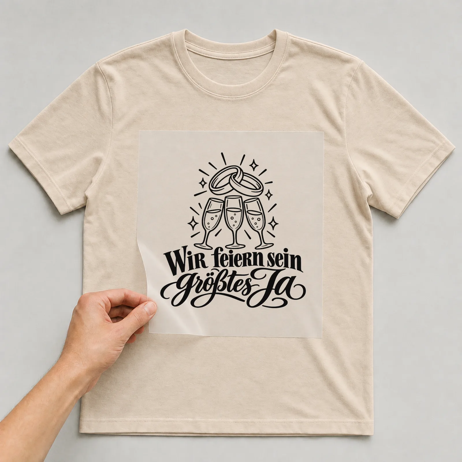 Bügelbild „WIR feiern sein größtes Ja“ auf beigem T-Shirt, Folie wird aufgelegt
