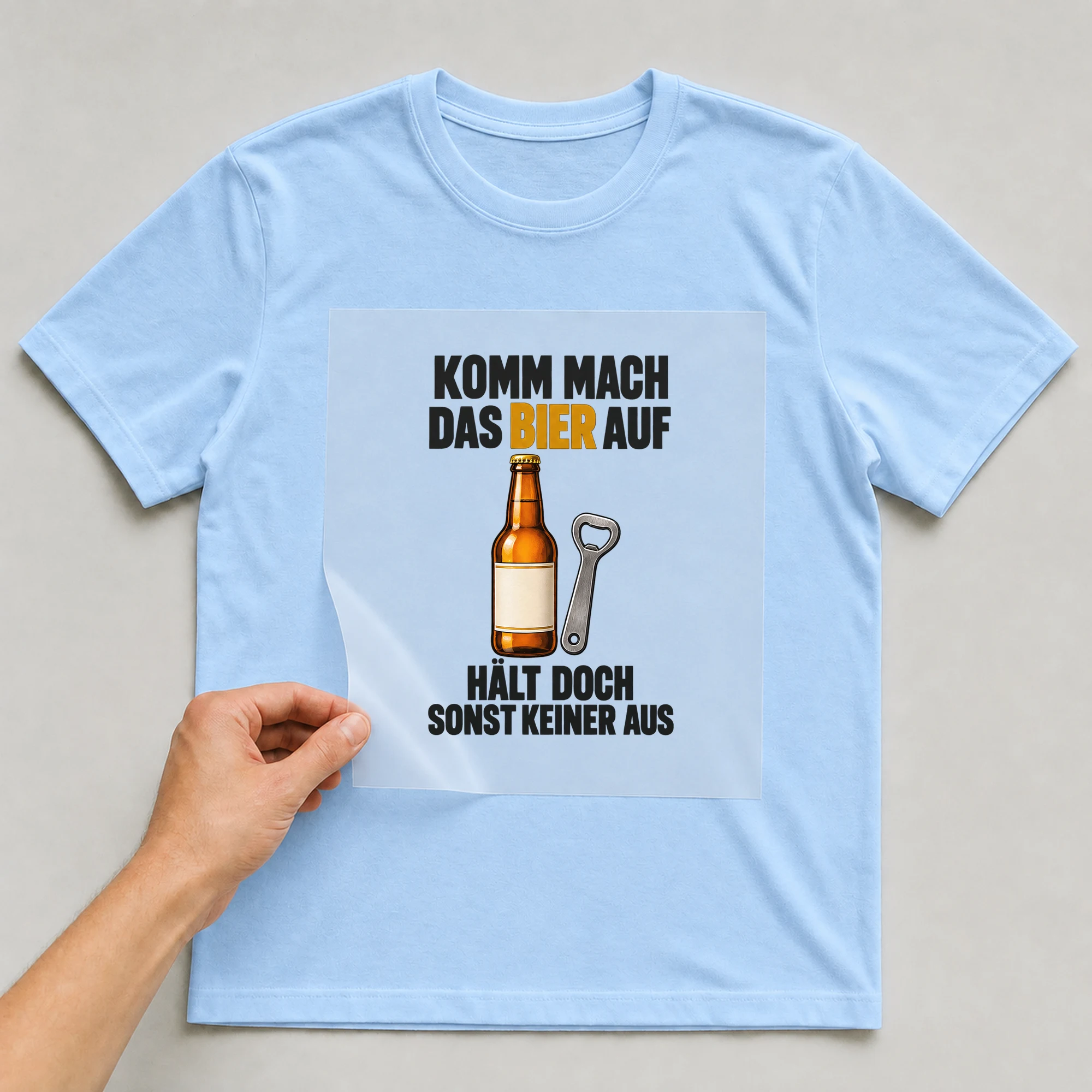 Bügelbild „Komm mach das Bier auf hält doch sonst keiner aus“ auf babyblauem T-Shirt, Folie wird aufgelegt