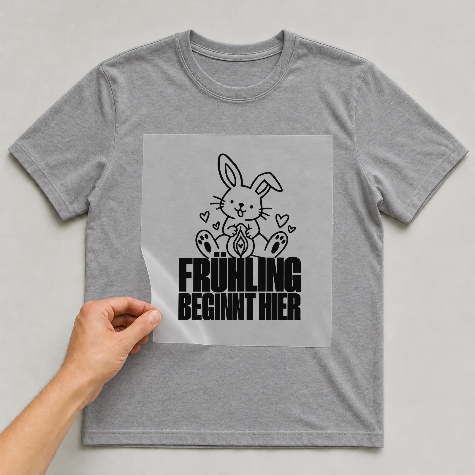 Bügelbild „Frühling beginnt hier“ auf grauem T-Shirt, Folie wird aufgelegt