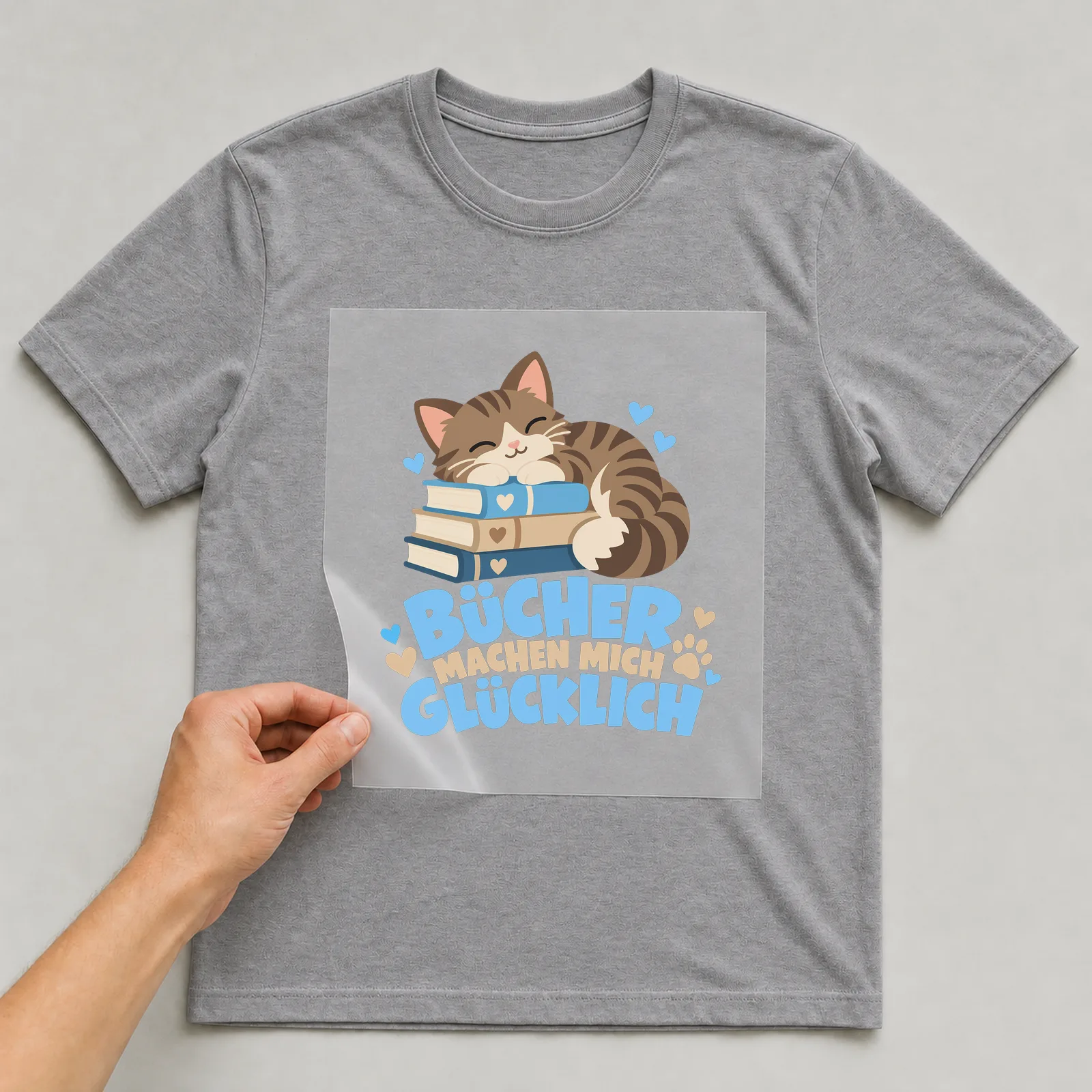 Bügelbild „Bücher machen mich glücklich“ auf grauem T-Shirt, Folie wird aufgelegt