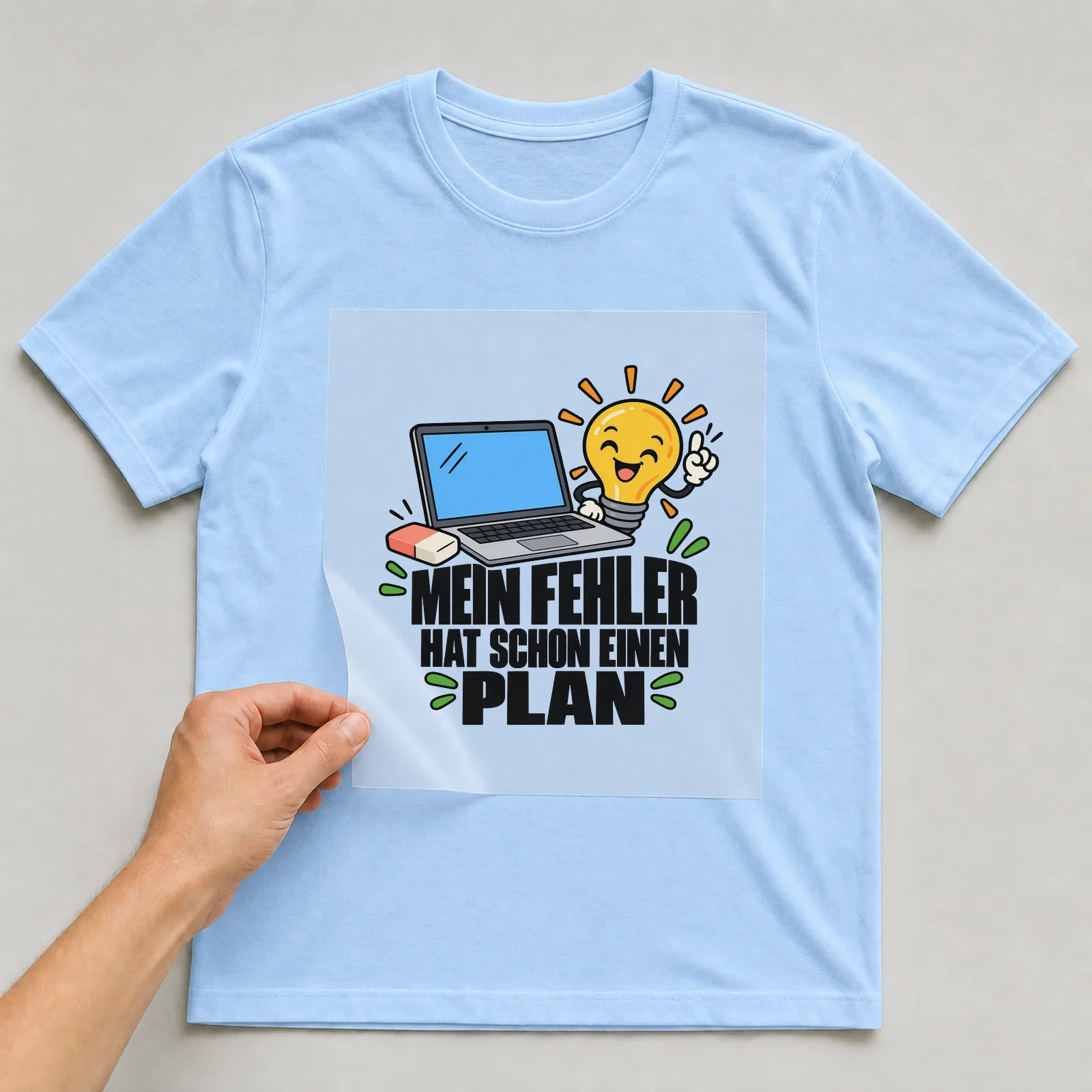 Bügelbild „Mein Fehler hat schon einen Plan“ auf hellblauem T-Shirt, Folie wird aufgelegt