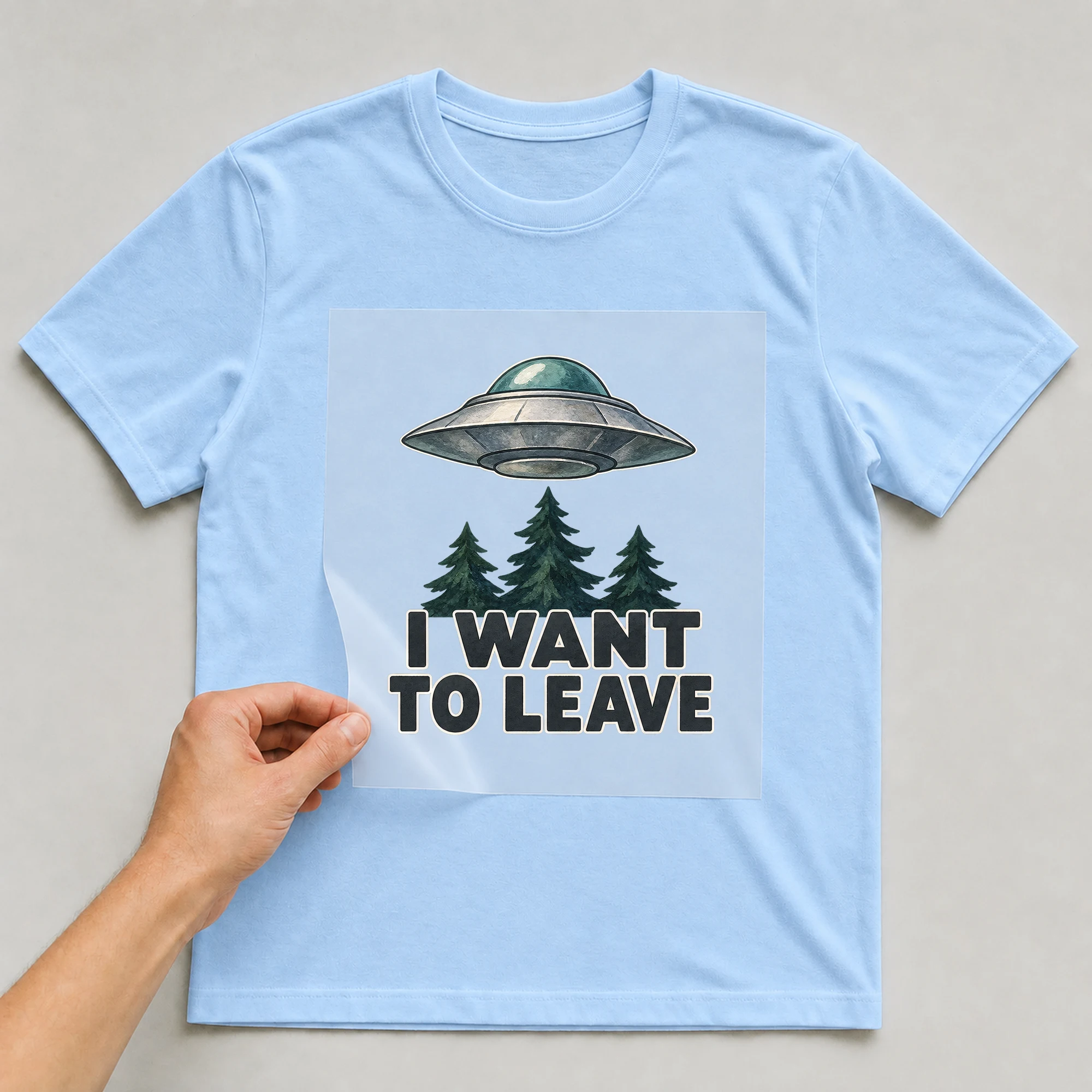 Bügelbild „I WANT TO LEAVE“ auf babyblauem T-Shirt, Folie wird aufgelegt