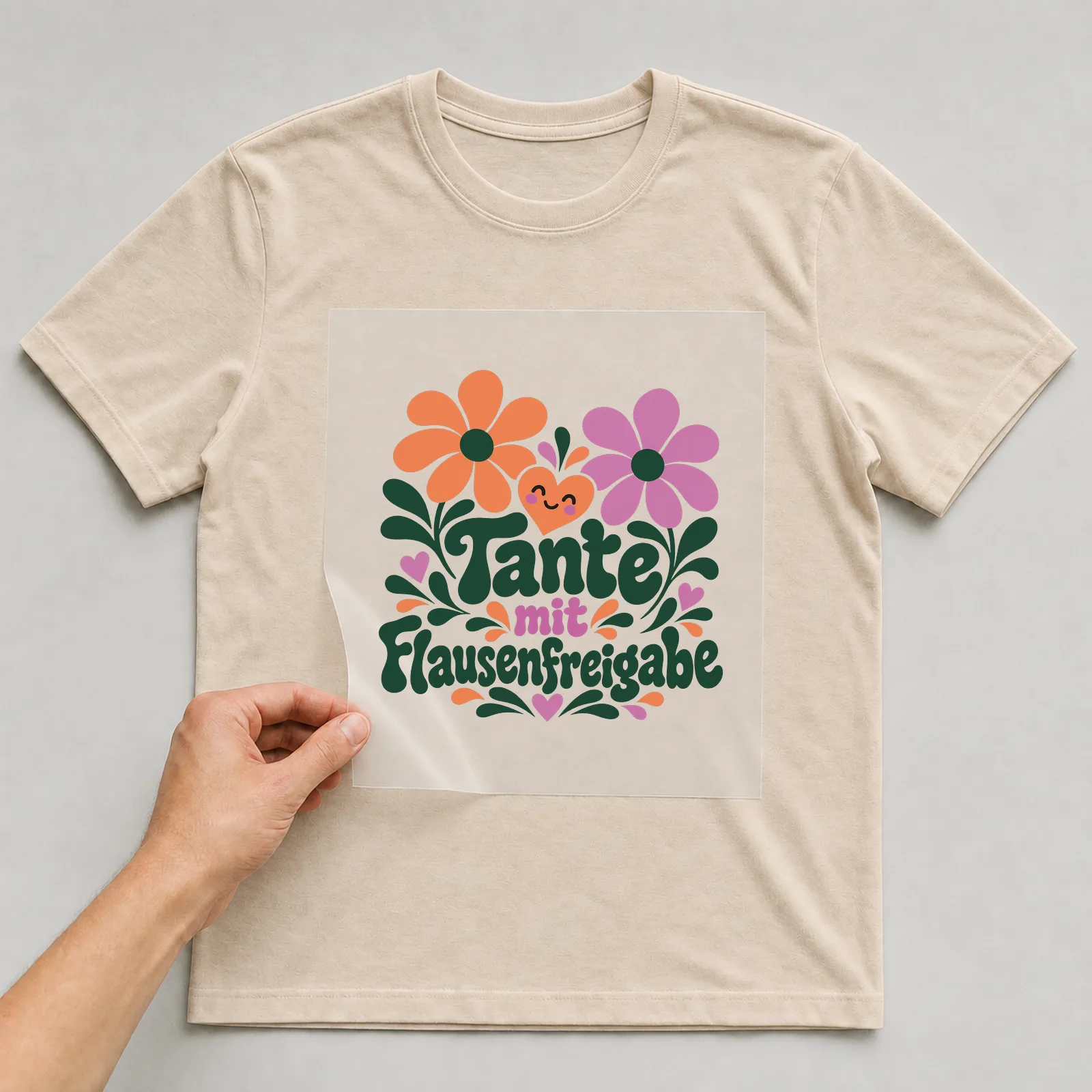 Bügelbild „Tante mit Flausenfreigabe“ auf beigem T-Shirt, Folie wird aufgelegt