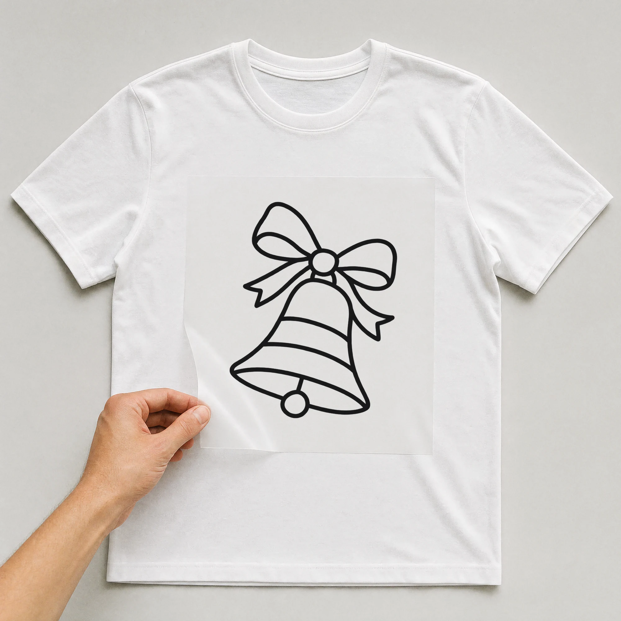 Bügelbild „Weihnachtsglocke“ auf weißem T-Shirt, Folie wird aufgelegt