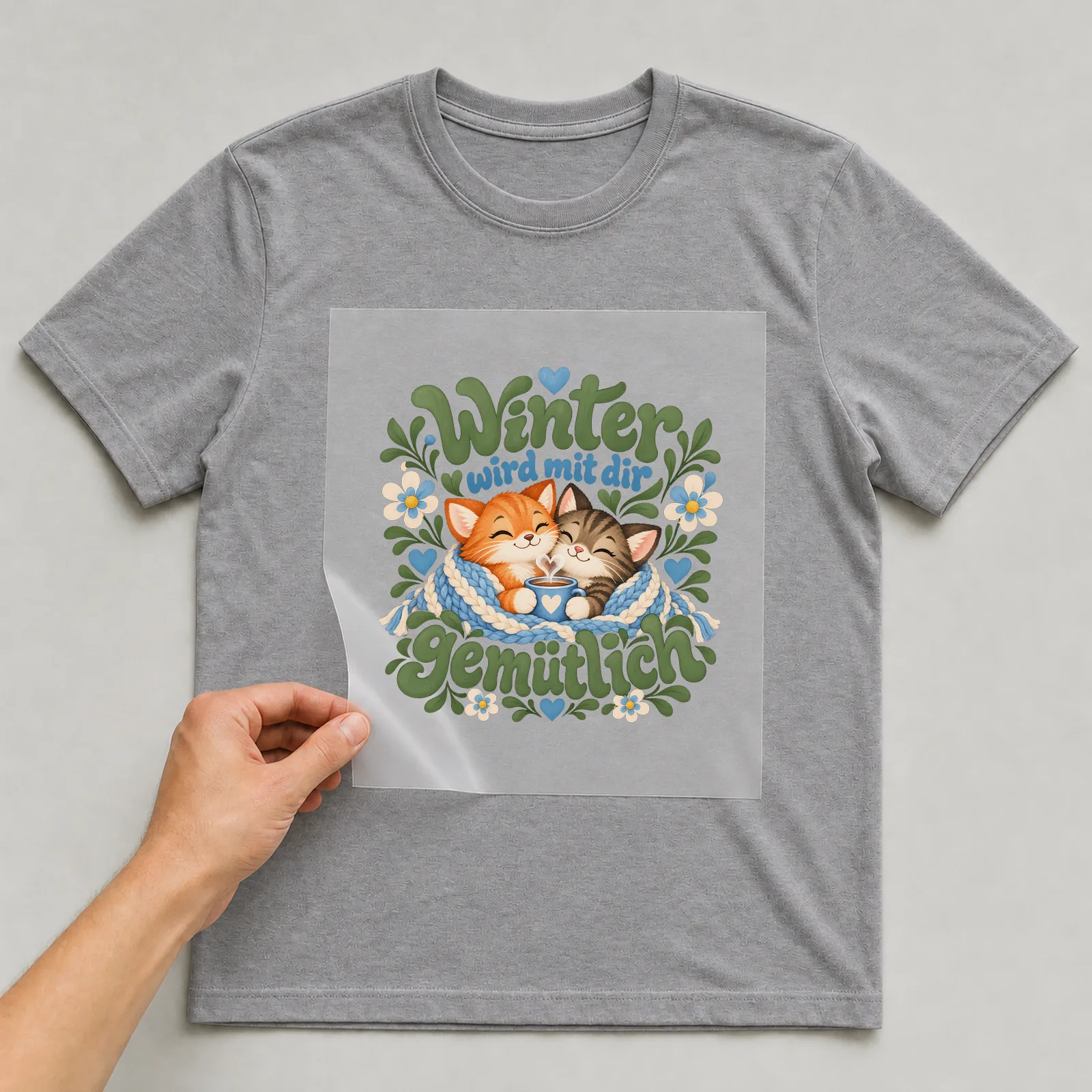 Bügelbild „Winter wird mit dir gemütlich“ auf grauem T-Shirt, Folie wird aufgelegt
