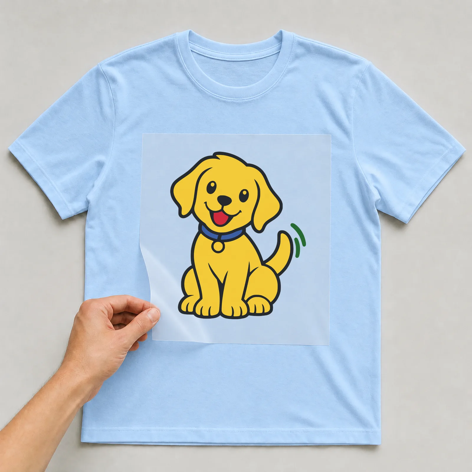 Bügelbild Labrador im Comic-Stil auf hellblauem T-Shirt, Folie wird aufgelegt