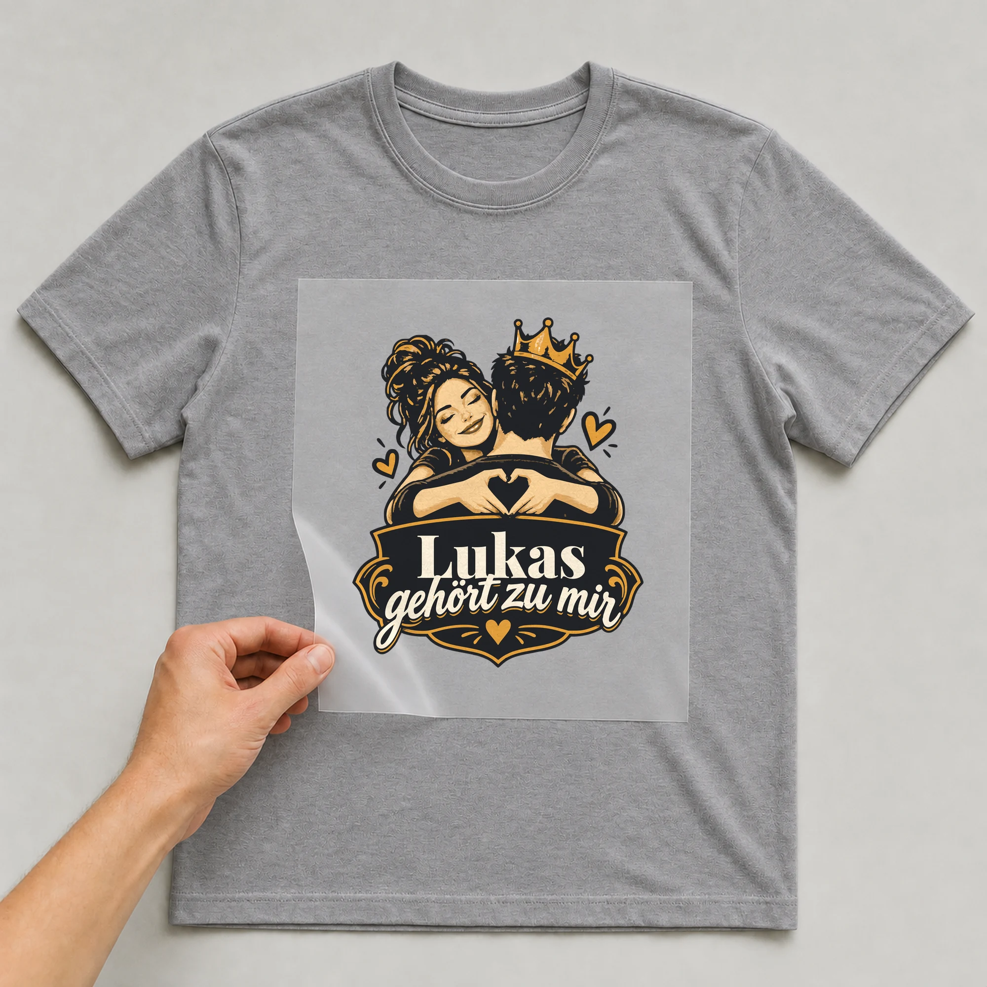 Bügelbild Gehört zu mir mit Name auf grauem T-Shirt, Folie wird aufgelegt