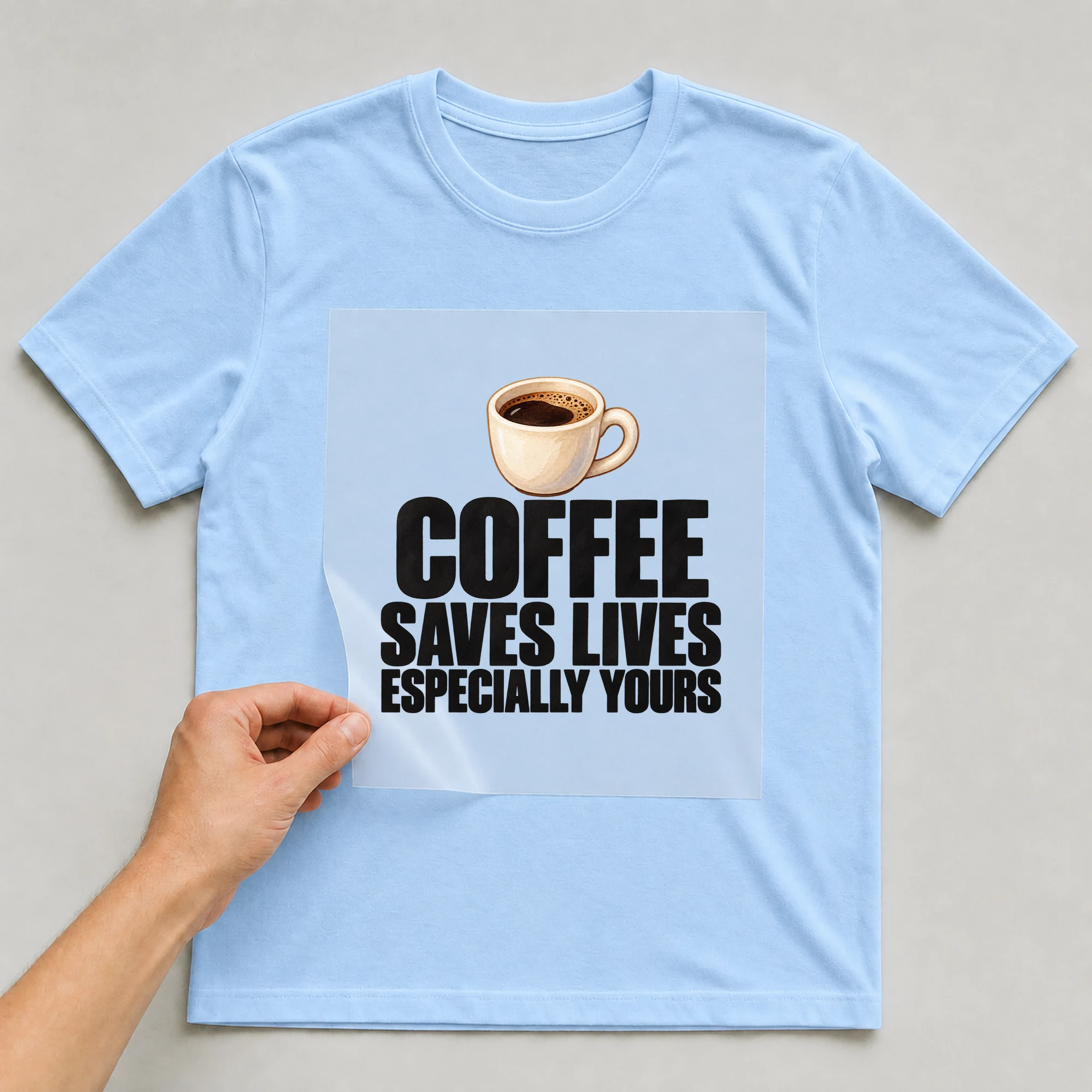 Bügelbild „Coffee Saves Lives Especially Yours“ auf babyblauem T-Shirt, Folie wird aufgelegt