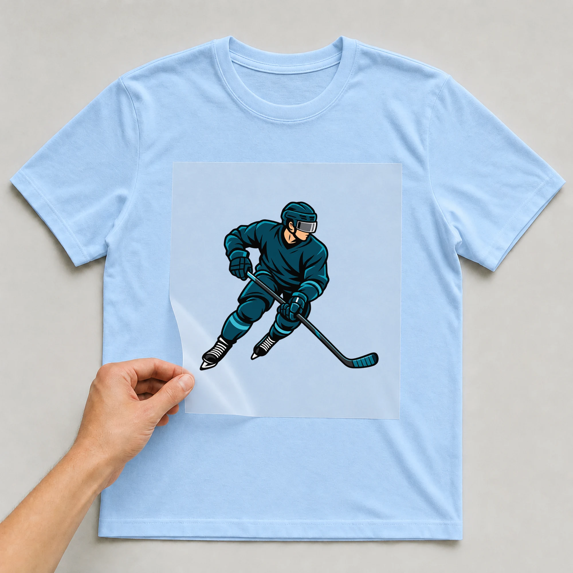 Bügelbild „Ice Hockey Spieler“ auf babyblauem T-Shirt, Folie wird aufgelegt