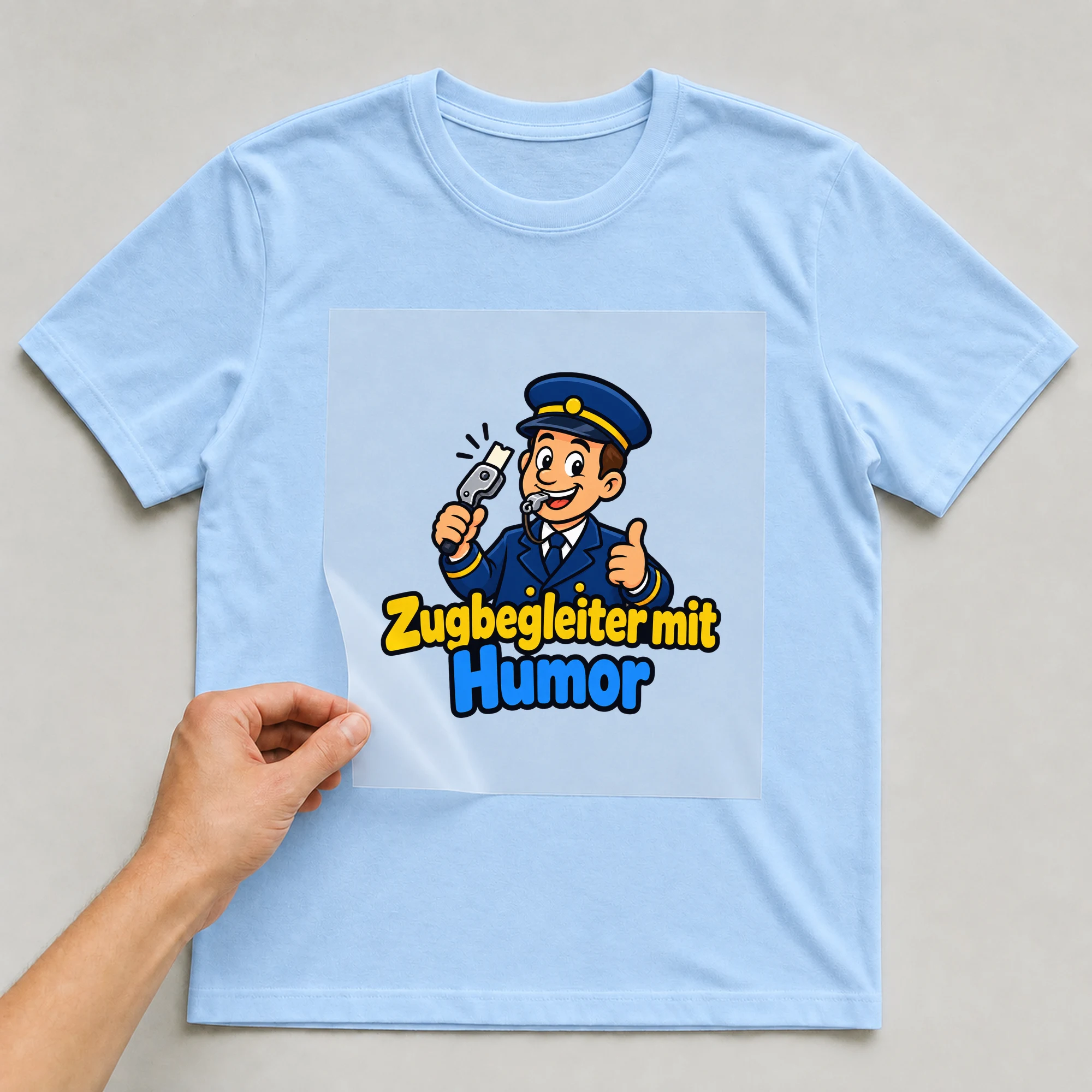Bügelbild „Zugbegleiter mit Humor“ auf babyblauem T-Shirt, Folie wird aufgelegt