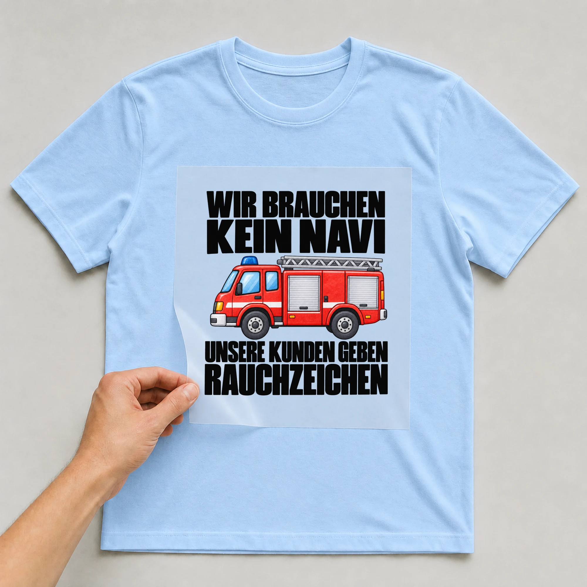 Bügelbild „Wir Brauchen Kein Navi Unsere Kunden Geben Rauchzeichen“ auf babyblauem T-Shirt, Folie wird aufgelegt