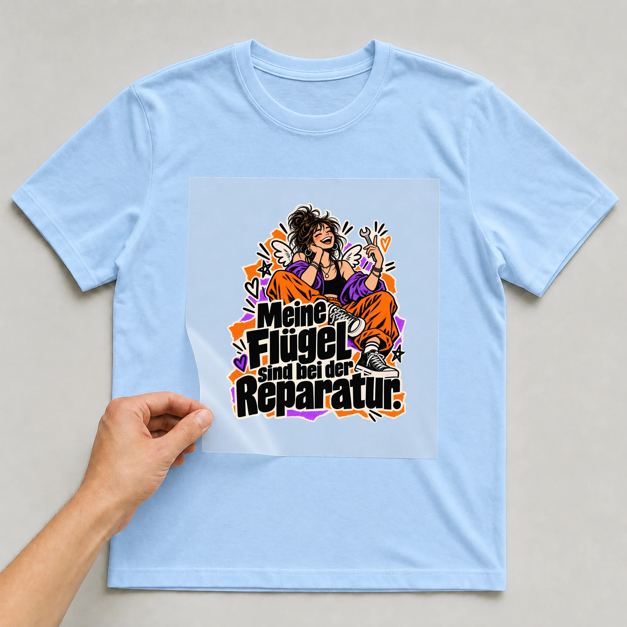 Bügelbild „Meine Flügel sind bei der Reparatur.“ auf babyblauem T-Shirt, Folie wird aufgelegt