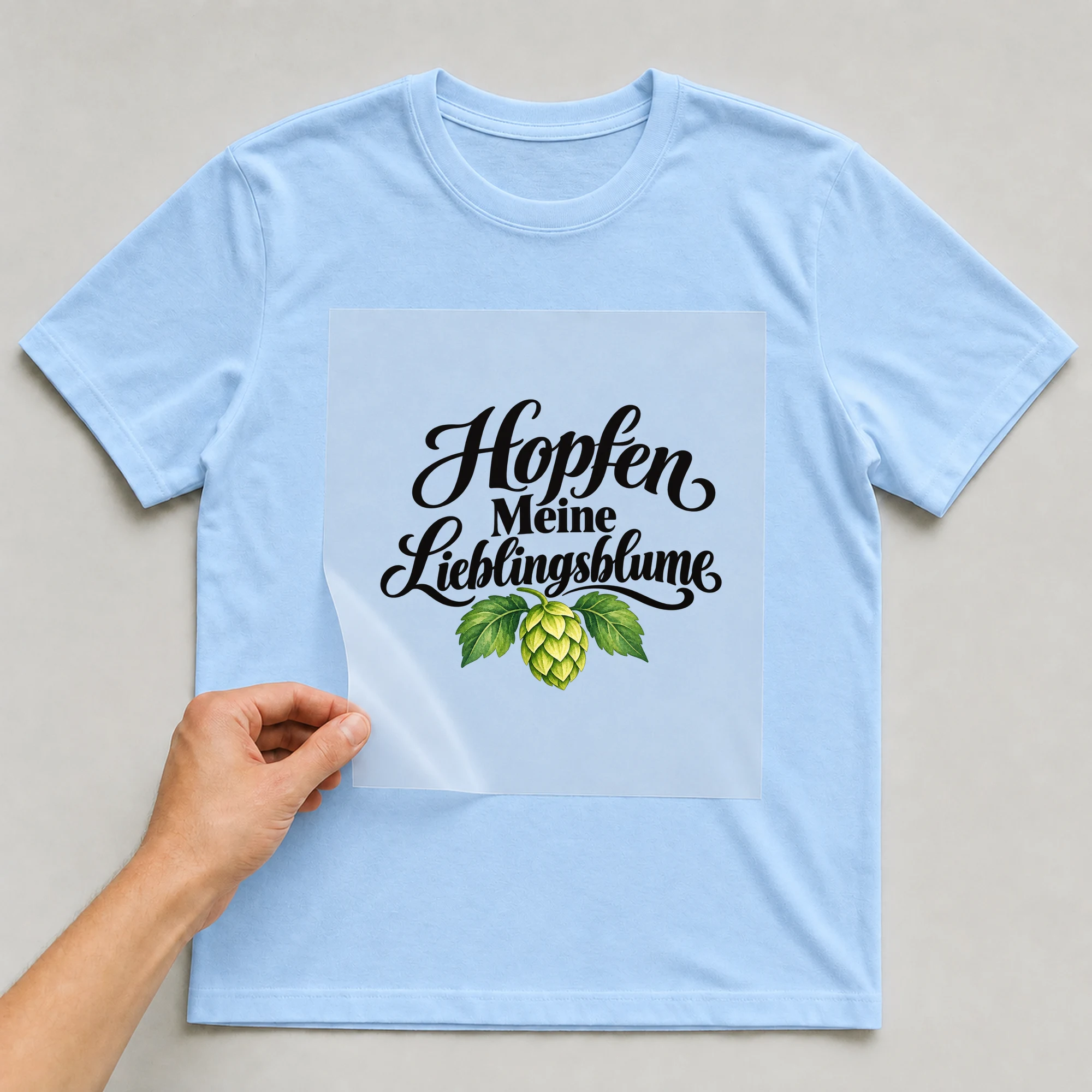 Bügelbild „Hopfen Meine Lieblingsblume“ auf babyblauem T-Shirt, Folie wird aufgelegt