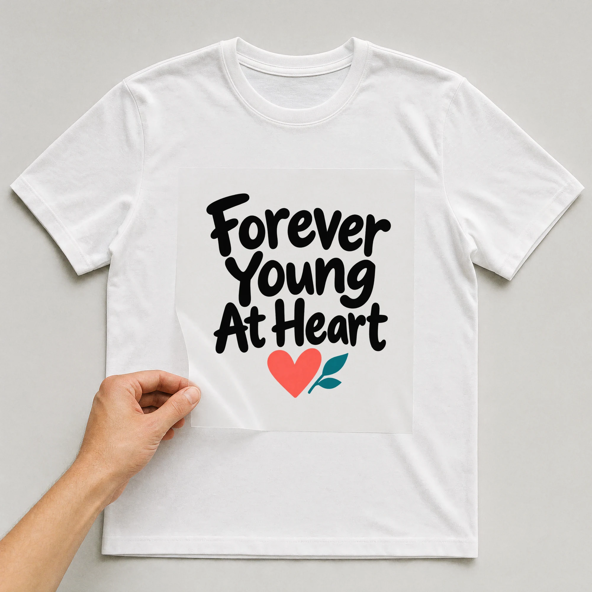 Bügelbild „Forever Young At Heart“ auf weißem T-Shirt, Folie wird aufgelegt