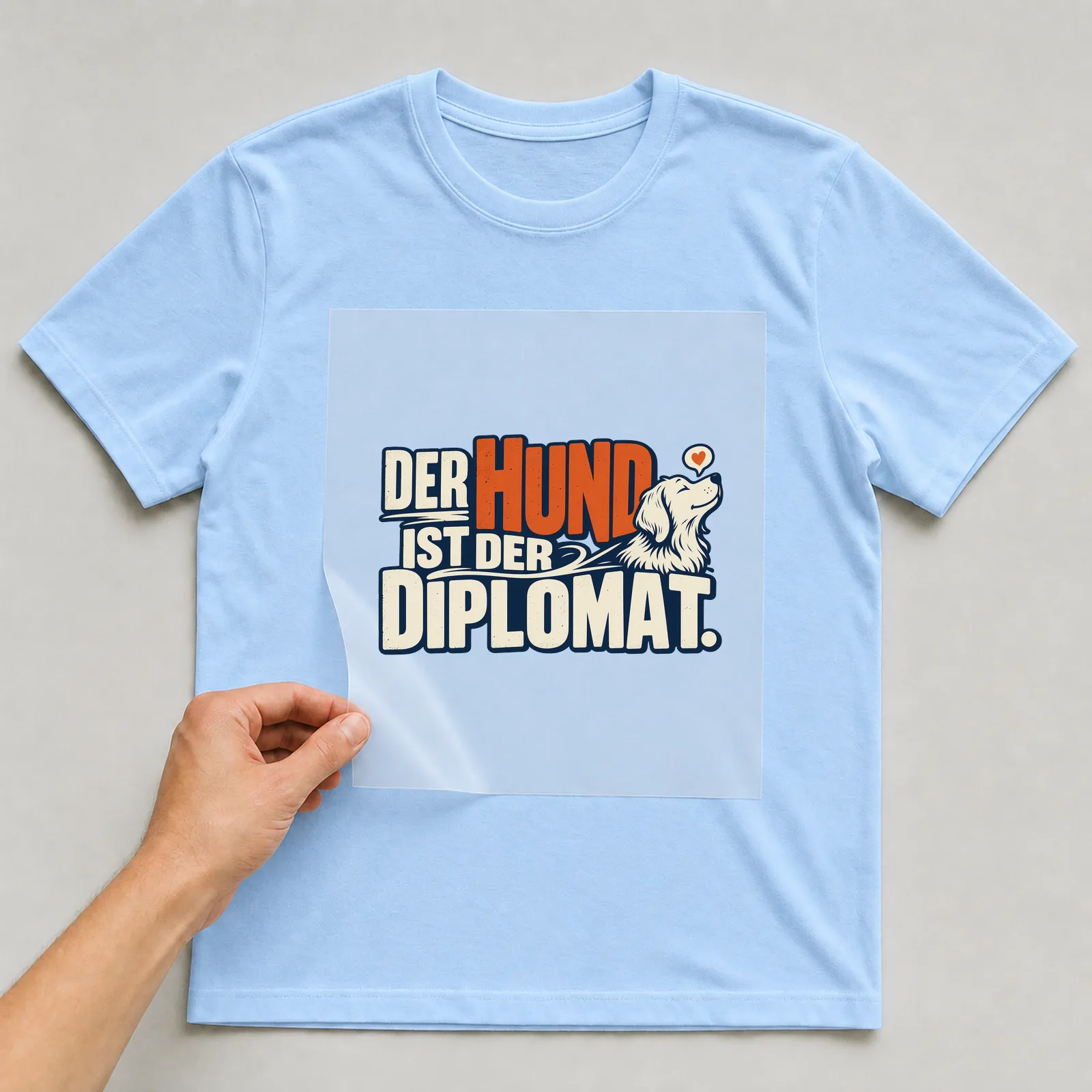 Bügelbild „Der Hund ist der Diplomat“ auf hellblauem T-Shirt, Folie wird aufgelegt
