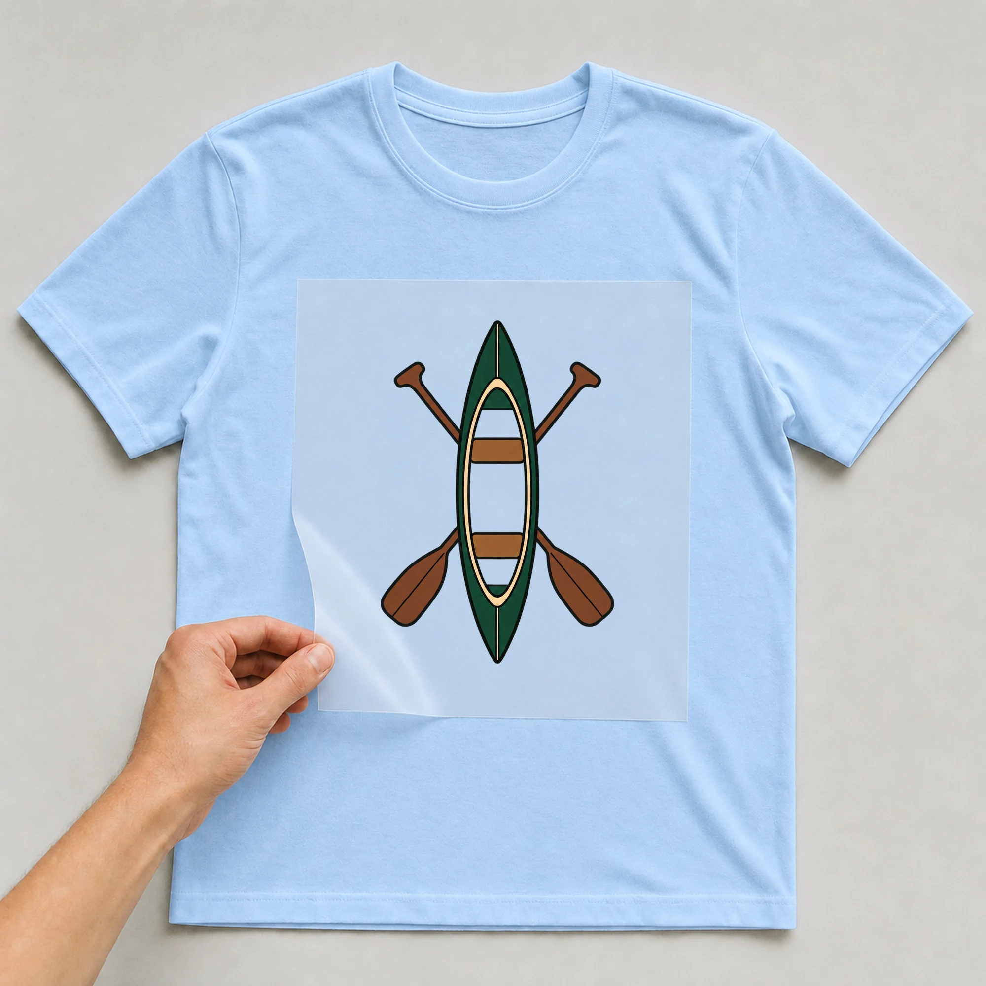 Bügelbild „Canoe Symbol“ auf babyblauem T-Shirt, Folie wird aufgelegt