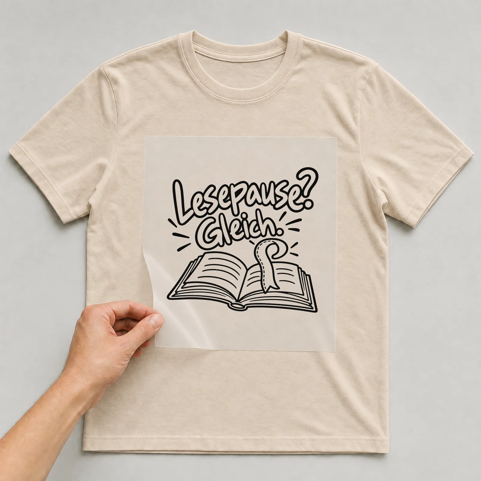 Bügelbild „Lesepause? Gleich.“ auf beigem T-Shirt, Folie wird aufgelegt