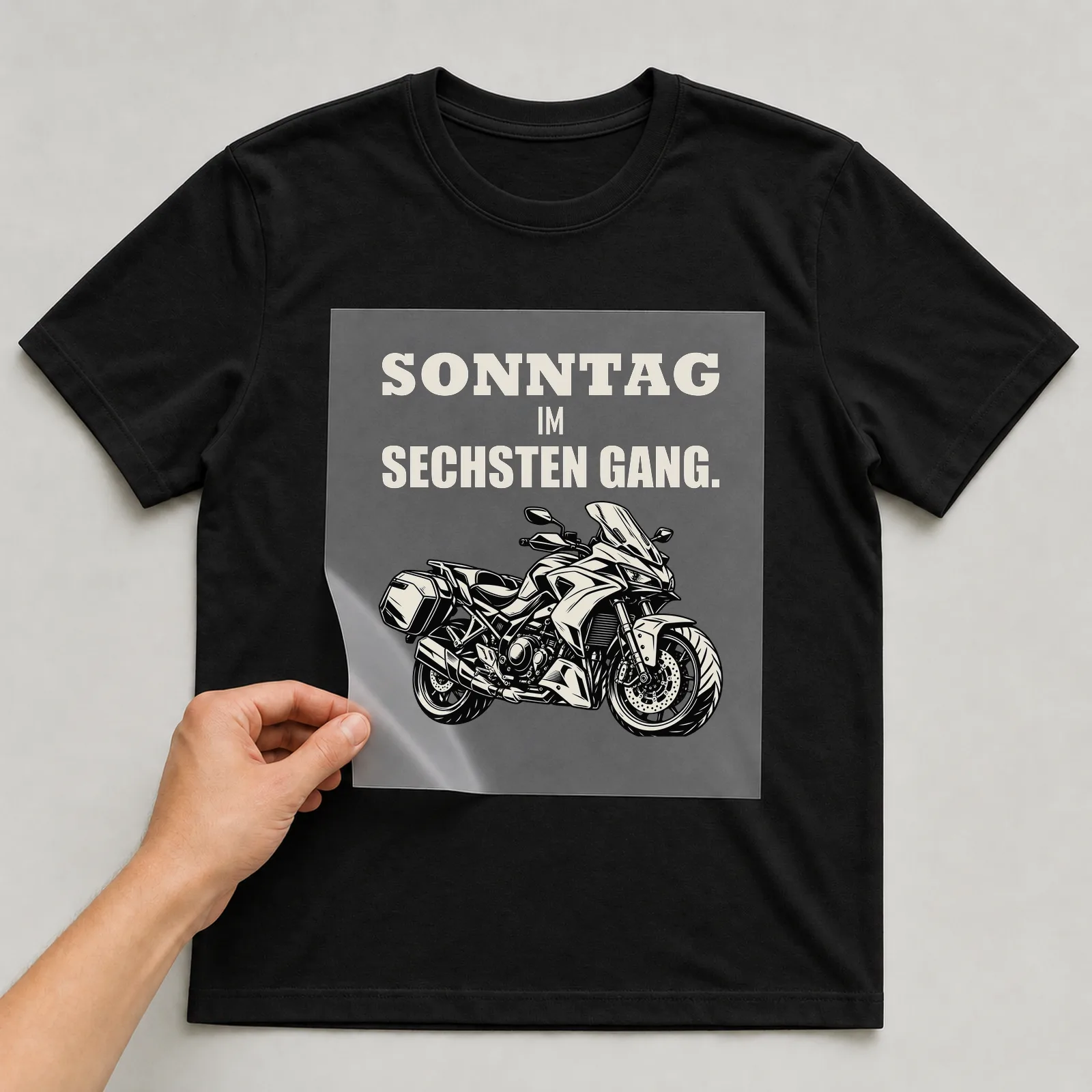 Bügelbild „Sonntag im sechsten Gang“ auf schwarzem T-Shirt, Folie wird aufgelegt