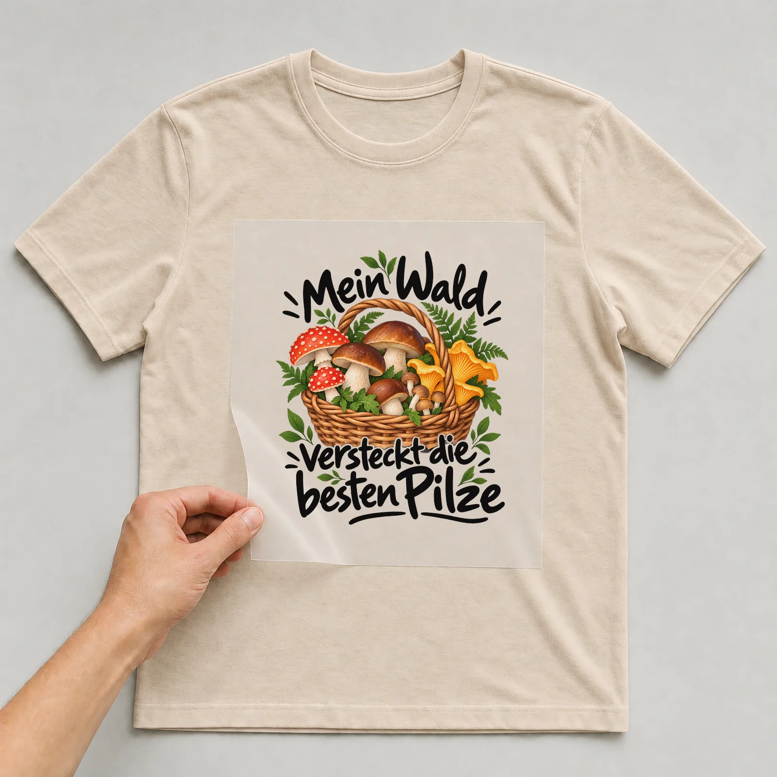 Bügelbild „Mein Wald versteckt die besten Pilze“ auf beigem T-Shirt, Folie wird aufgelegt