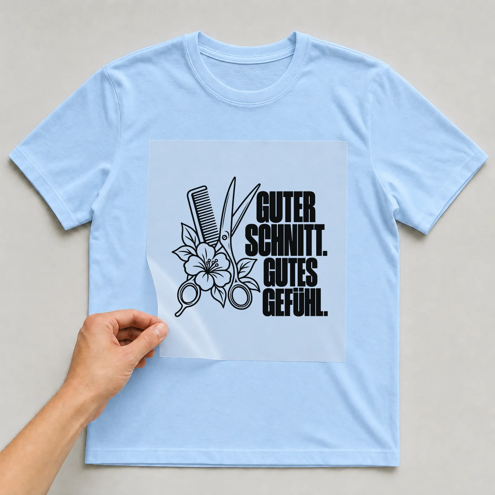 Bügelbild „Guter Schnitt. Gutes Gefühl.“ auf hellblauem T-Shirt, Folie wird aufgelegt