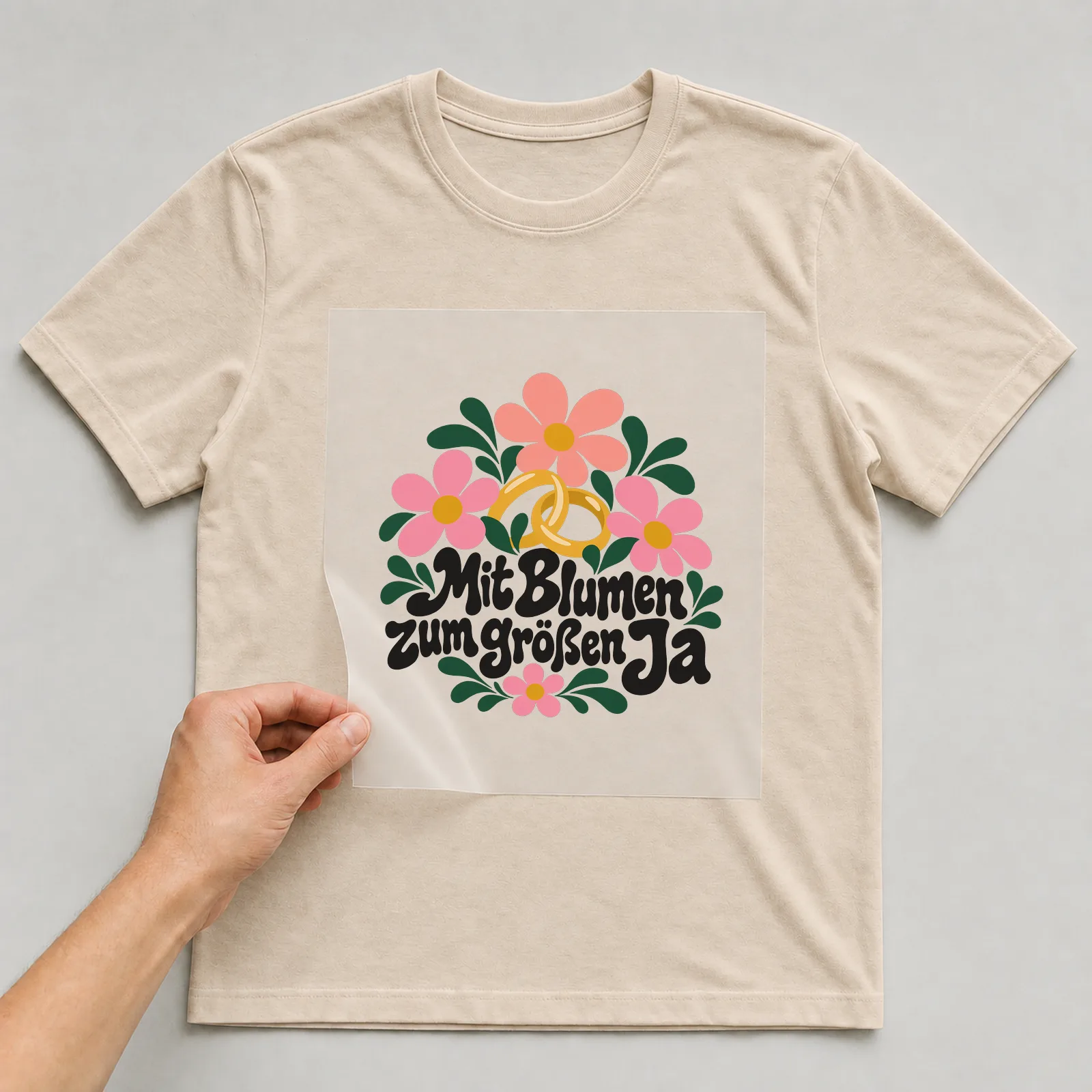 Bügelbild „Mit Blumen zum großen Ja“ auf beigem T-Shirt, Folie wird aufgelegt