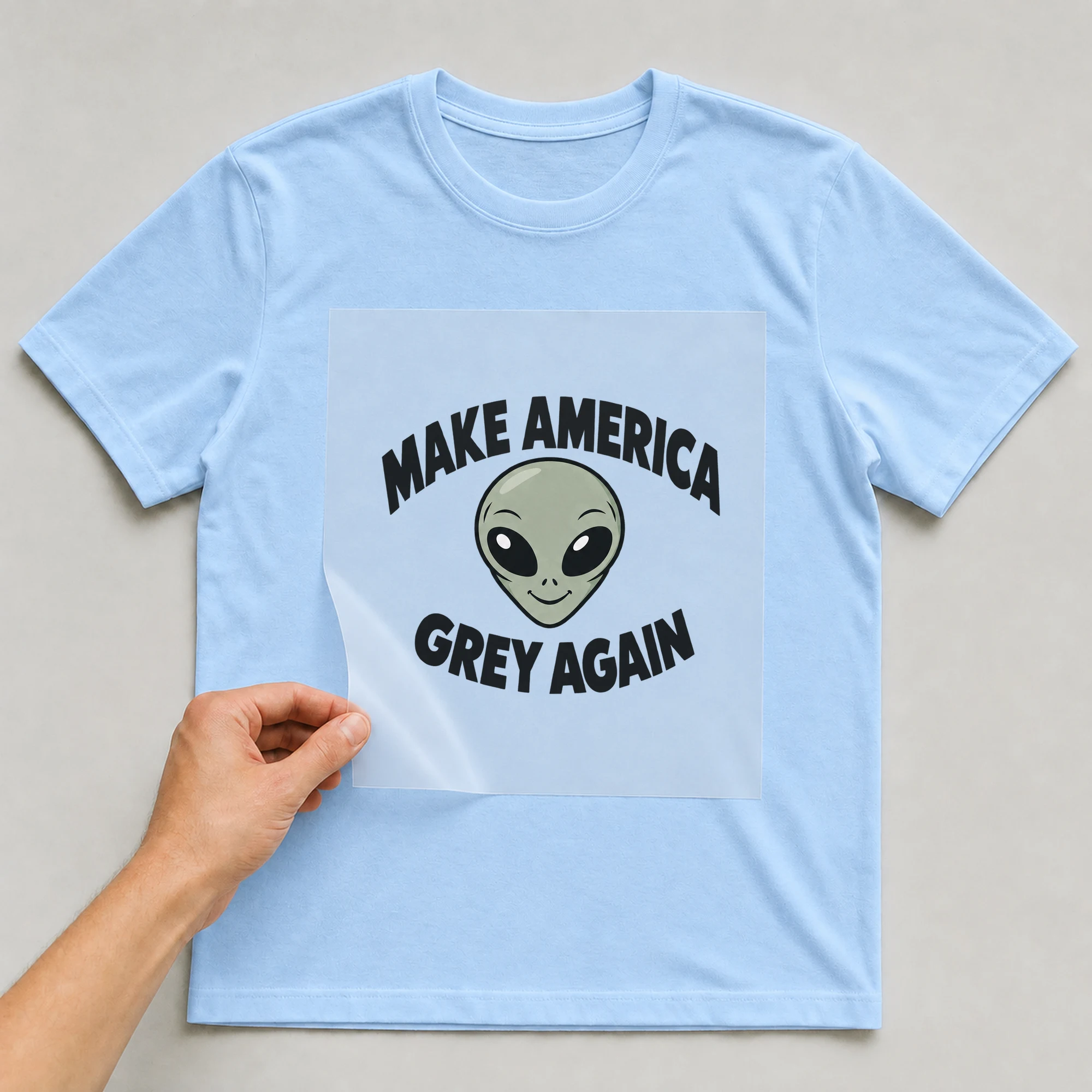 Bügelbild „Make America Grey Again“ auf babyblauem T-Shirt, Folie wird aufgelegt