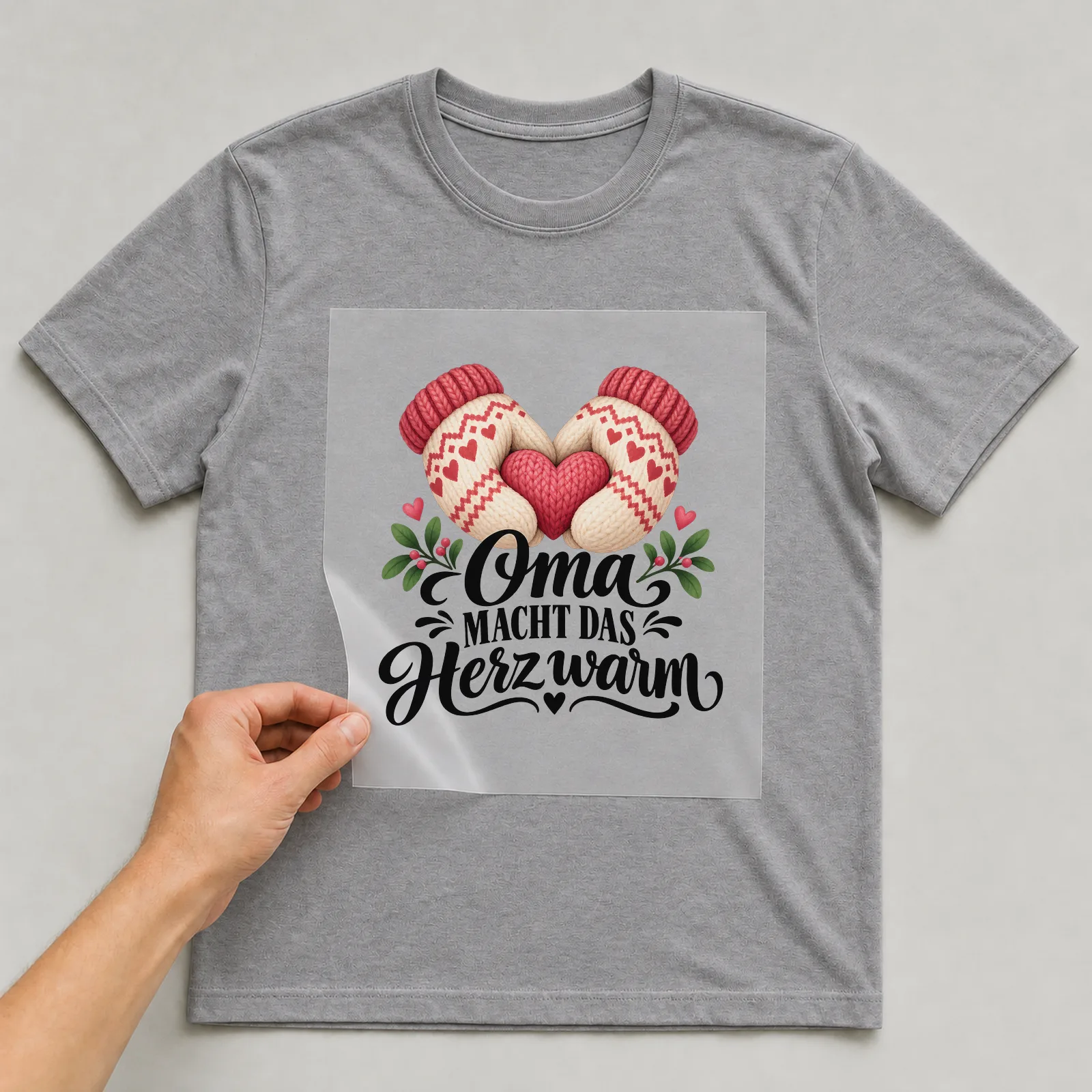 Bügelbild „Oma macht das Herz warm“ auf grauem T-Shirt, Folie wird aufgelegt
