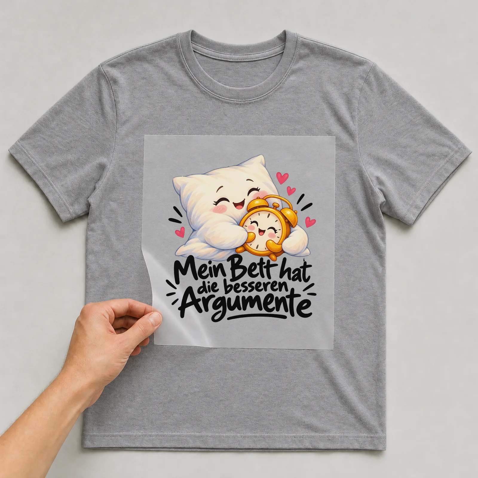 Bügelbild „Mein Bett hat die besseren Argumente“ auf grauem T-Shirt, Folie wird aufgelegt