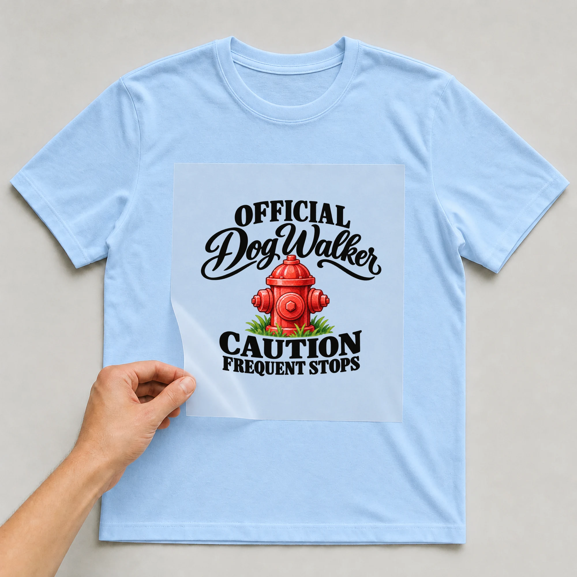 Bügelbild „Official Dog Walker Caution Frequent Stops“ auf babyblauem T-Shirt, Folie wird aufgelegt