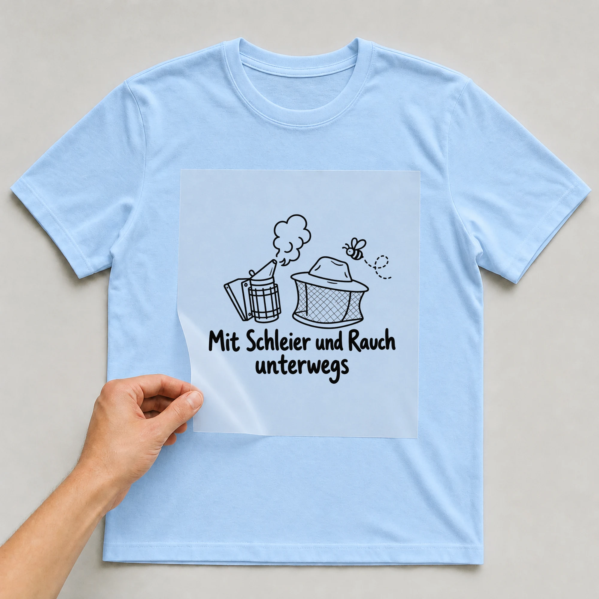 Bügelbild „Mit Schleier und Rauch unterwegs“ auf babyblauem T-Shirt, Folie wird aufgelegt