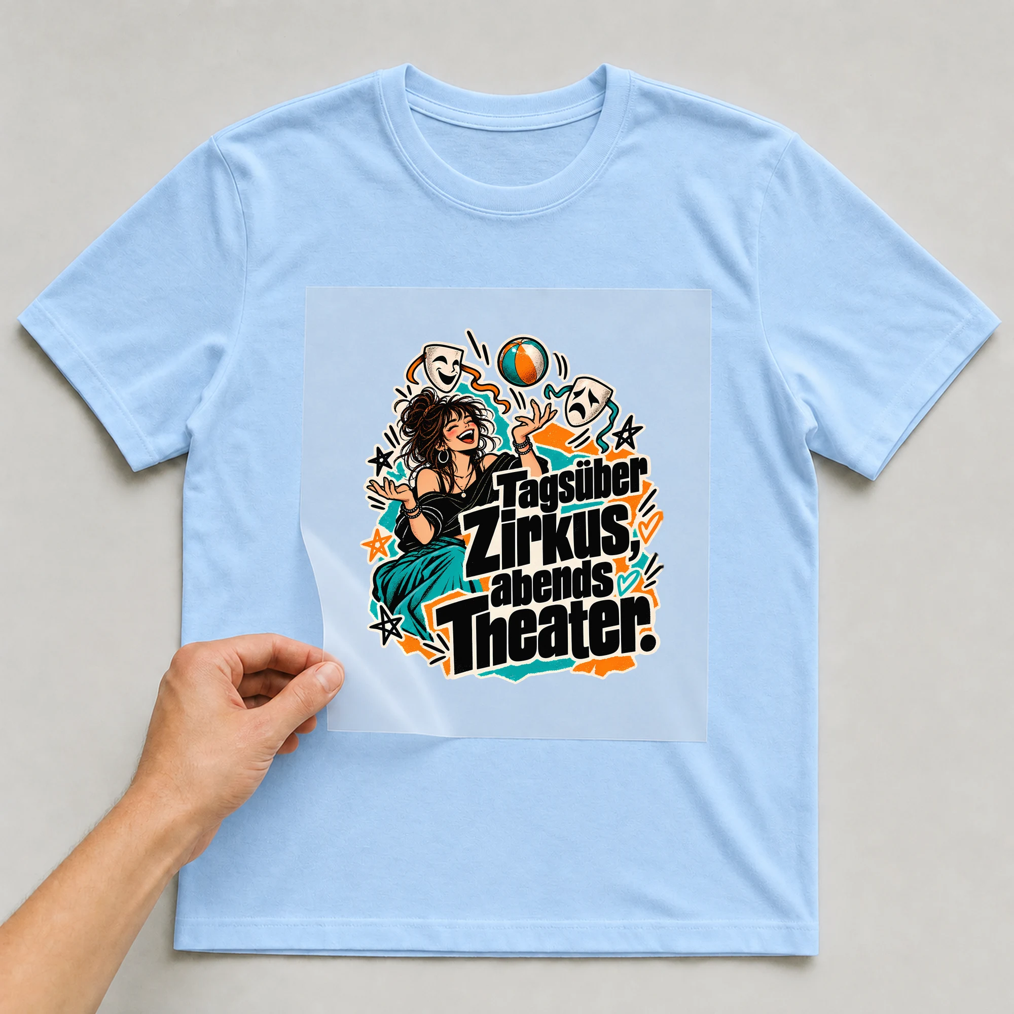 Bügelbild „Tagsüber Zirkus, abends Theater.“ auf babyblauem T-Shirt, Folie wird aufgelegt