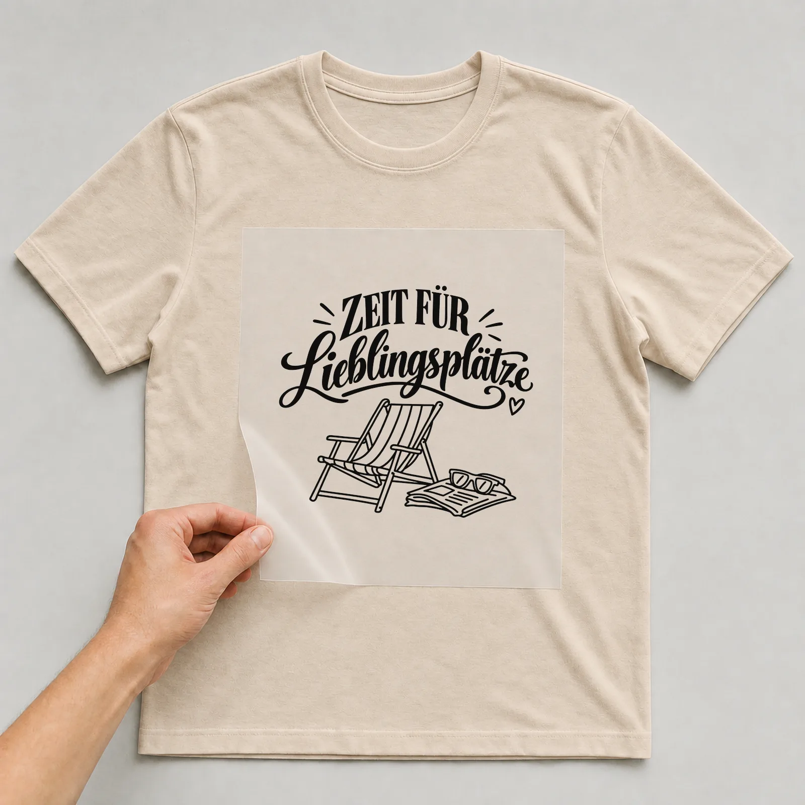Bügelbild „Zeit für Lieblingsplätze“ auf beigem T-Shirt, Folie wird aufgelegt