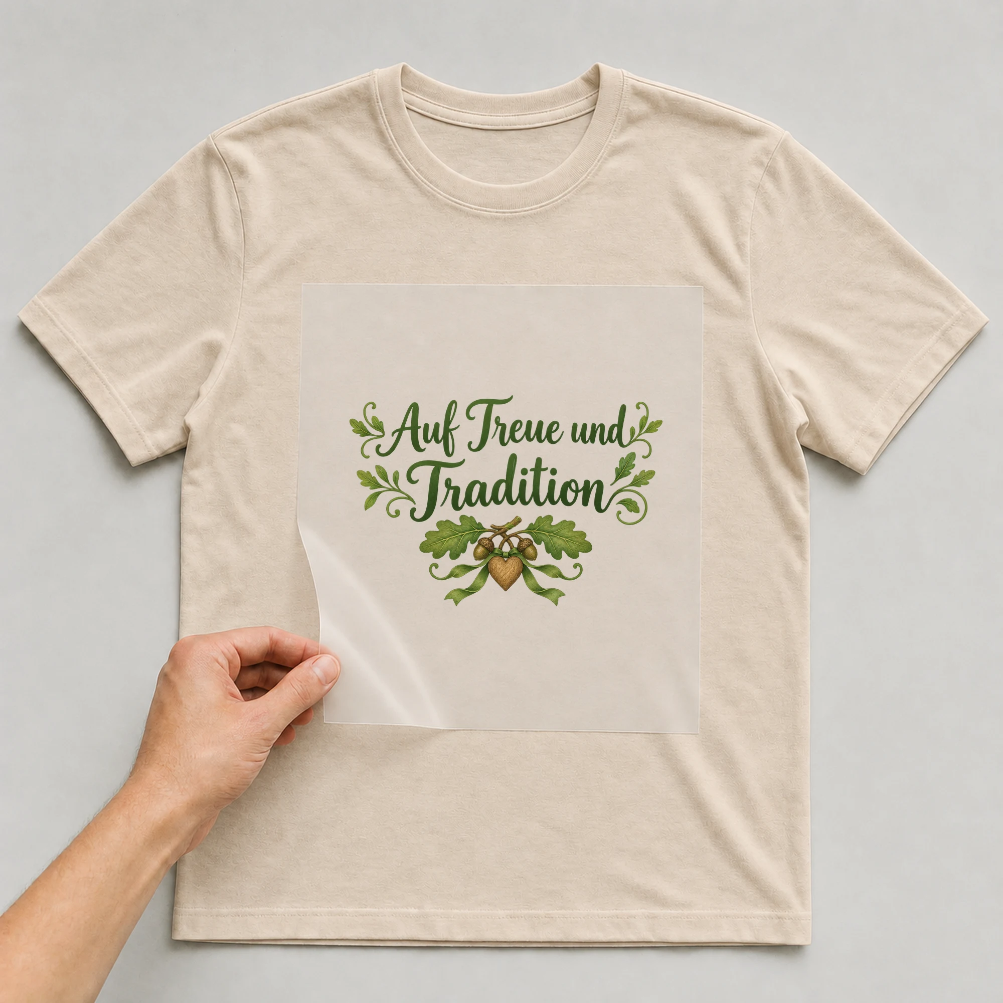 Bügelbild „Auf Treue und Tradition“ auf beigem T-Shirt, Folie wird aufgelegt
