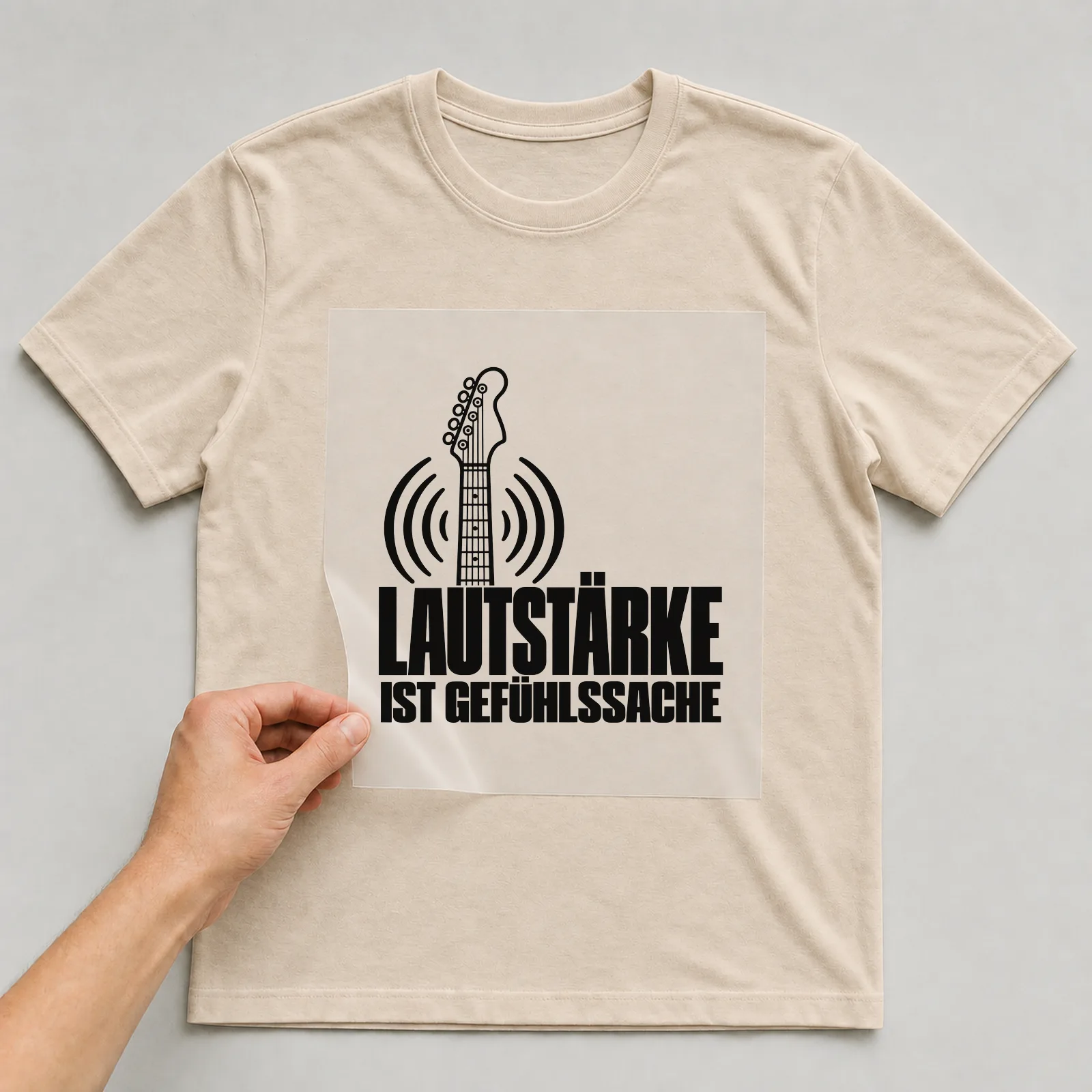 Bügelbild „Lautstärke ist Gefühlssache“ auf beigem T-Shirt, Folie wird aufgelegt