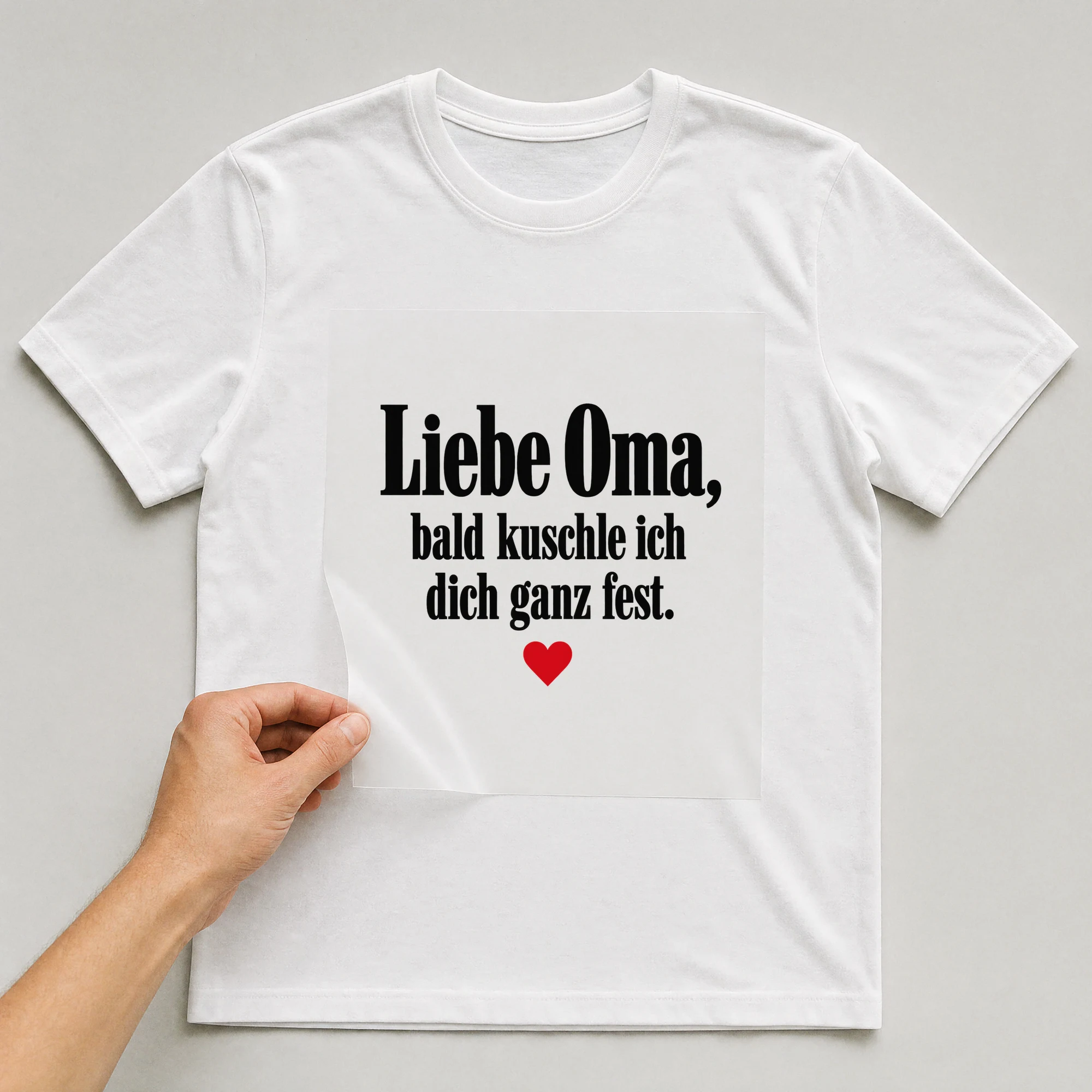 Bügelbild „Liebe Oma, bald kuschle ich dich ganz fest.“ auf weißem T-Shirt, Folie wird aufgelegt